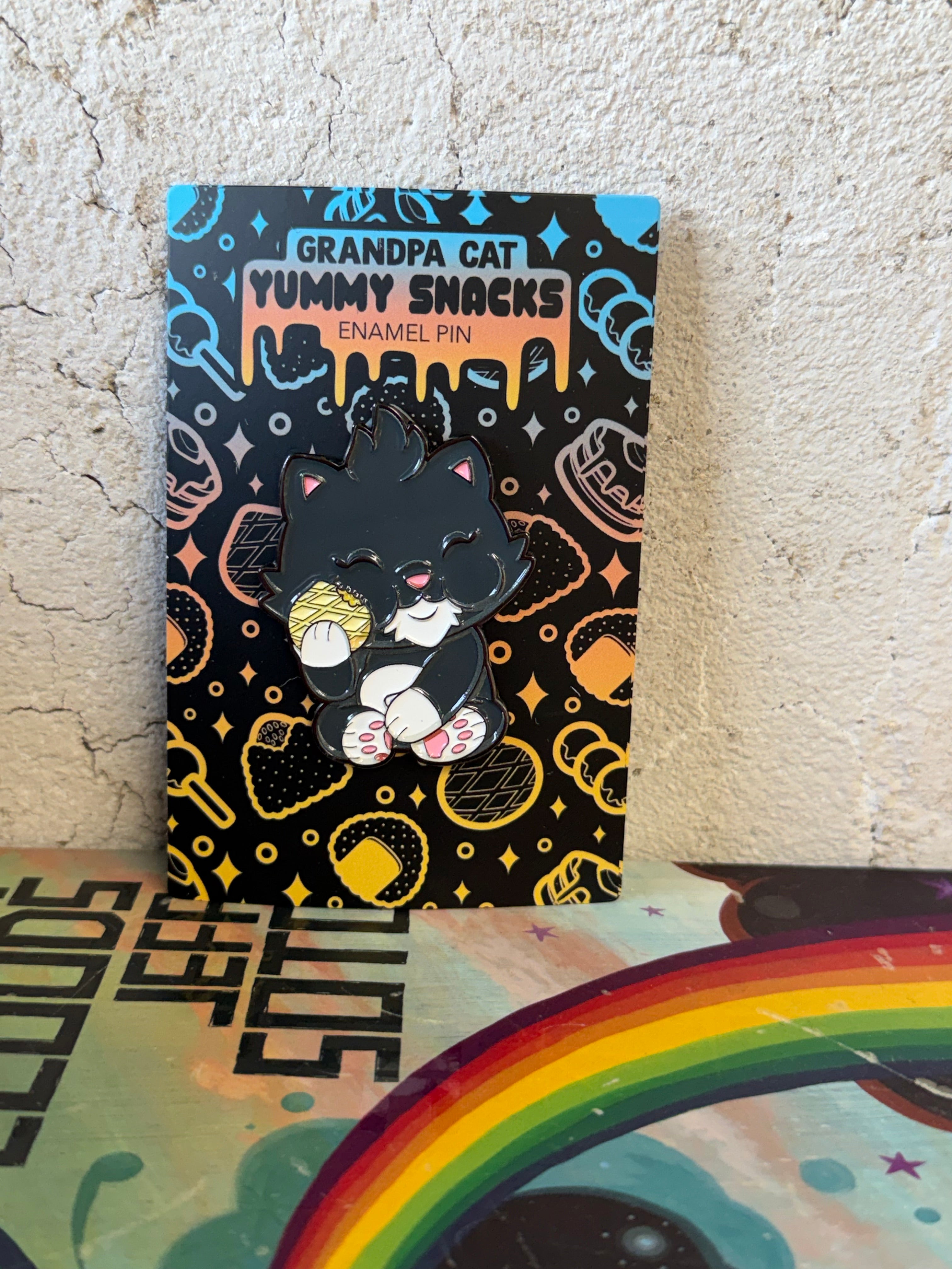 Grandpa Pin from the Japanese Snack Series features a cartoon cat enjoying a treat, mounted on a branded, cookie-patterned backing card.