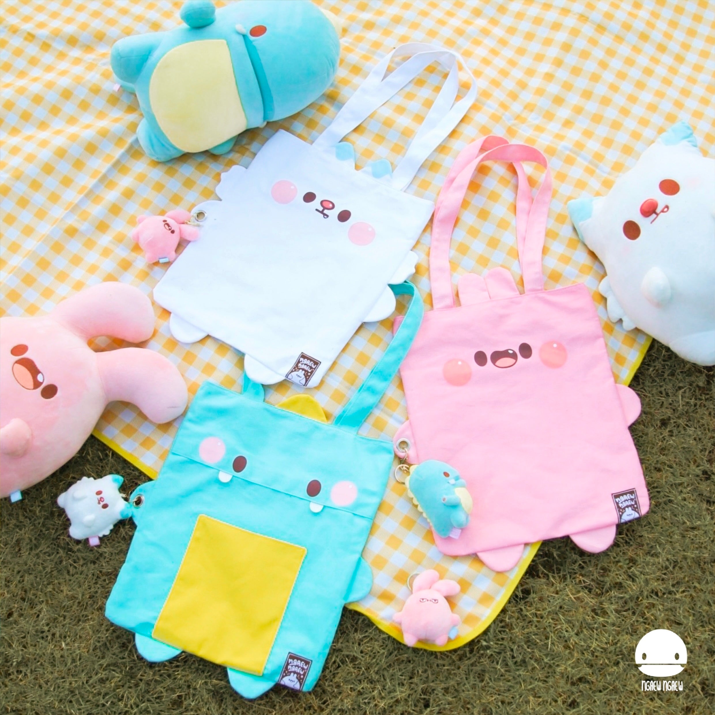 NGAEW NGAEW TOTE BAG with kawaii animal faces, ear/foot appliqués, and matching mini-plush keychains, displayed on a picnic blanket with plush toys.