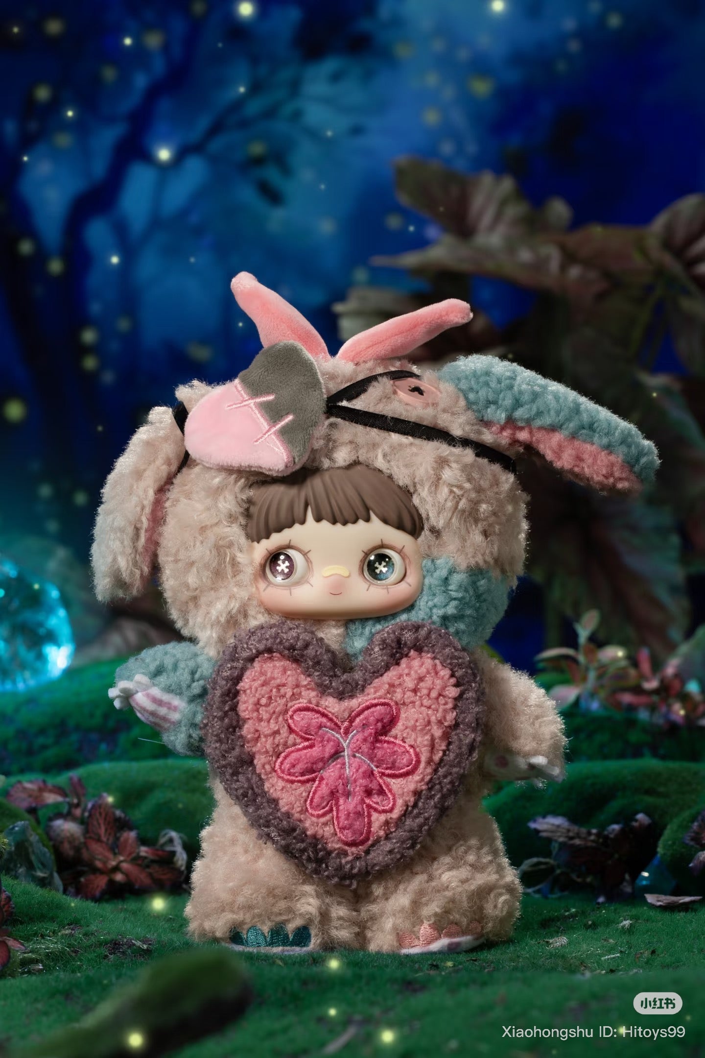 MayMei Symbiote Neverland Series keychain plush figure in a fluffy bunny costume with heart patch, posed in a whimsical moonlit-forest setting.