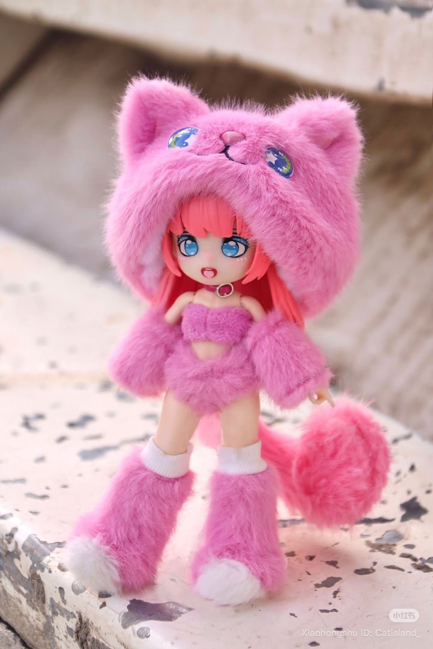 Cat Island-Black Cat Candy Cat Series figure in pink faux fur with cat-ear hood, pom-pom tail, on a chipped concrete ledge. Preorder for September 2025.