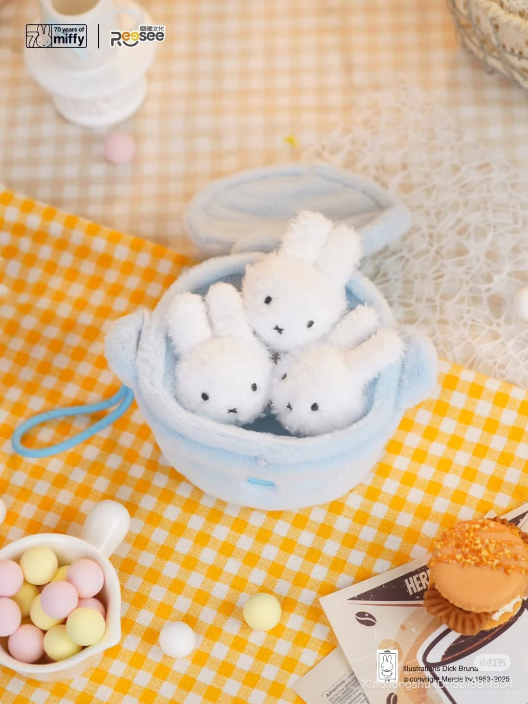 Miffy - Food Workshop Plush Keychain Blind Box featuring a baby-blue pouch with three tiny Miffy plushes, surrounded by candies and macaron, on gingham cloth.