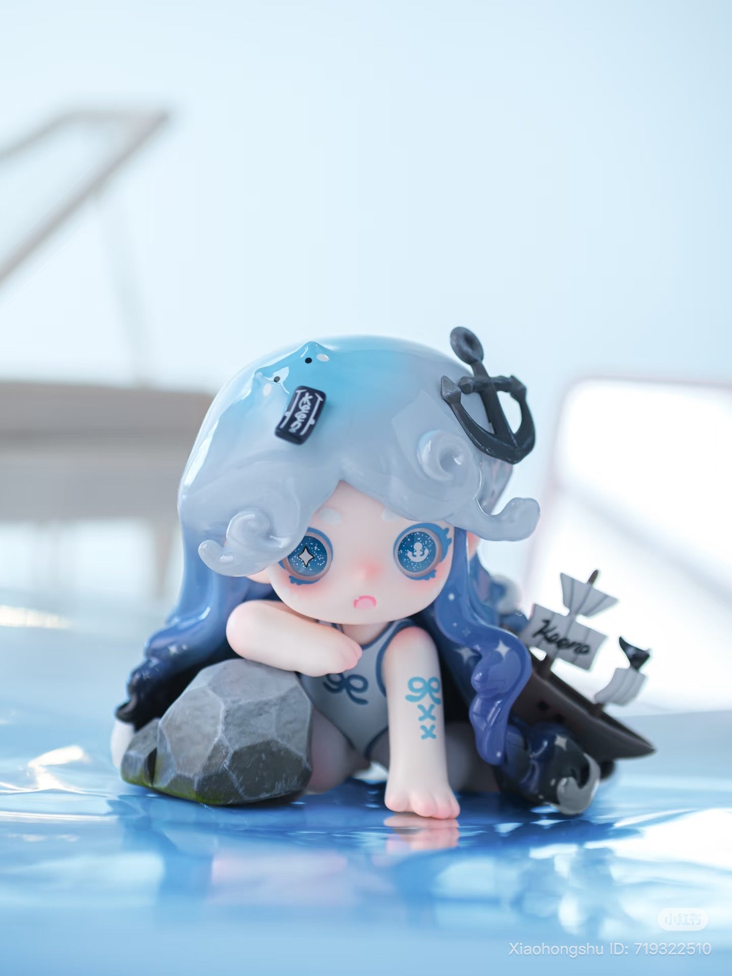 Keeno·Wish On The Sea Breeze figurine with blue hair, nautical elements, and glossy eyes, leaning on rock by water, from Strangecat Toys' blind box series.