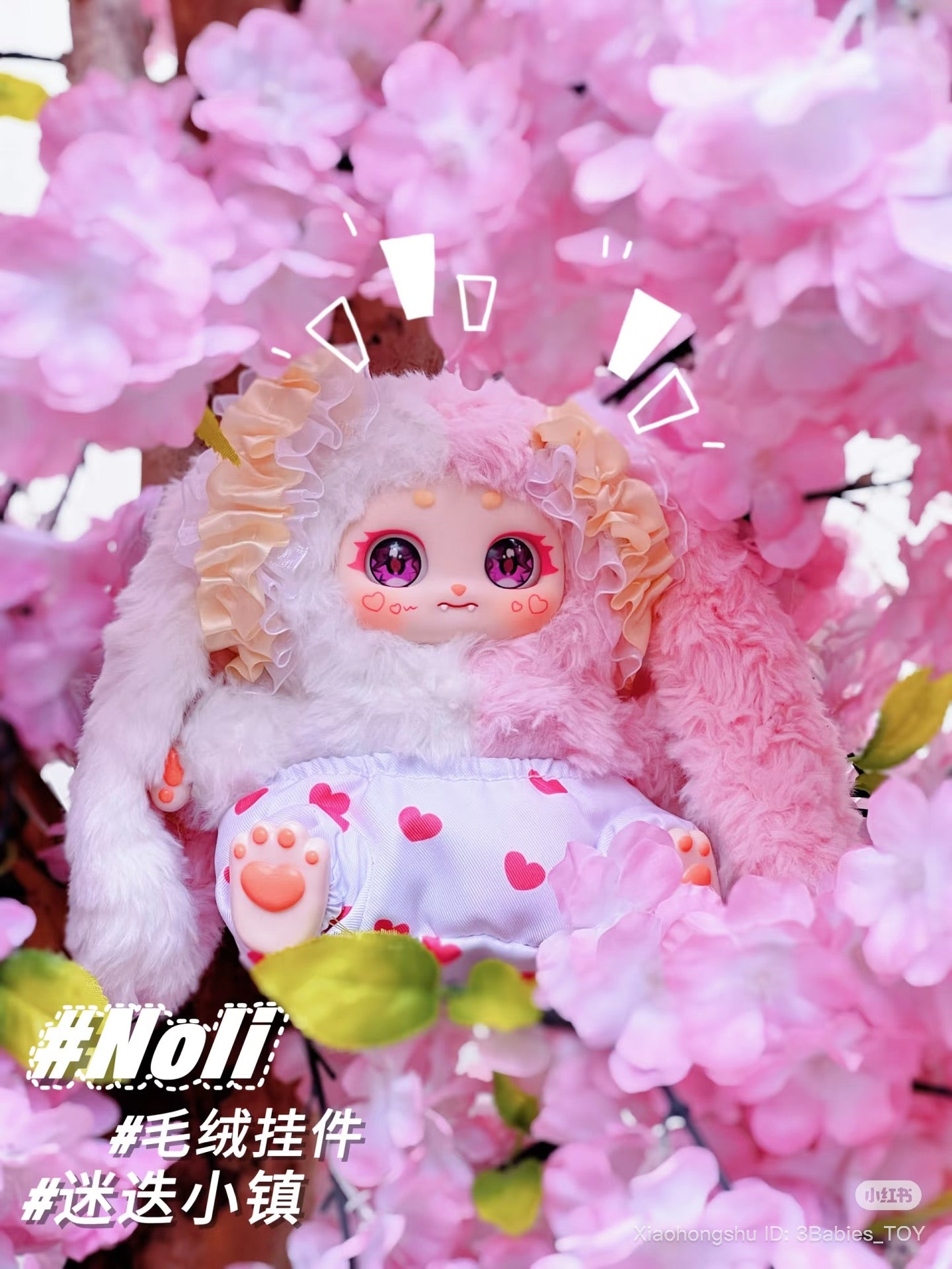 Baby Three - The Rosemary Town of Nori, a bunny-like plush accessory with floppy ears and big sparkly eyes, nestled among pink blossoms.