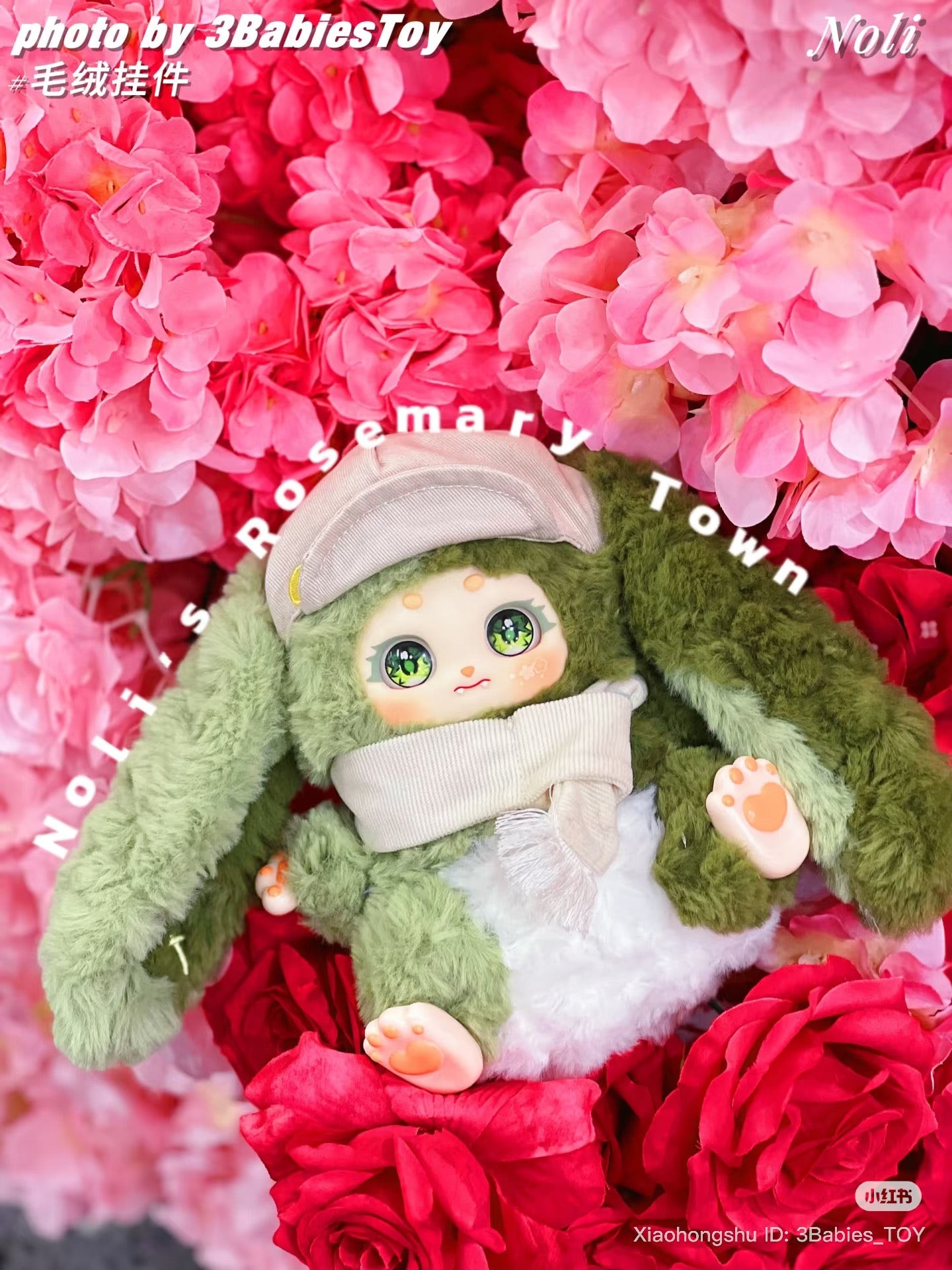 Baby Three - The Rosemary Town of Nori plush toy with sparkly eyes, cap, scarf, heart-shaped paws, atop bright flowers. Preorder for October 2025 shipment.