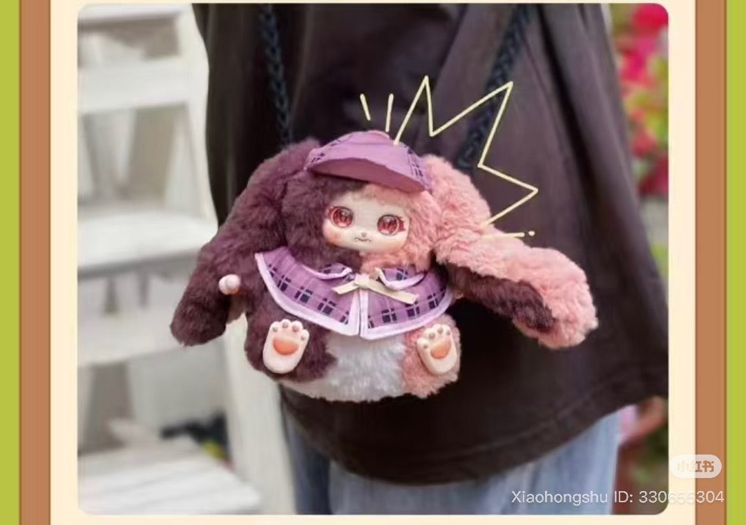 Baby Three - The Rosemary Town of Nori cross-body bag, styled as a plush bunny with floppy ears, glossy eyes, and plaid outfit, hanging by a chain strap. 