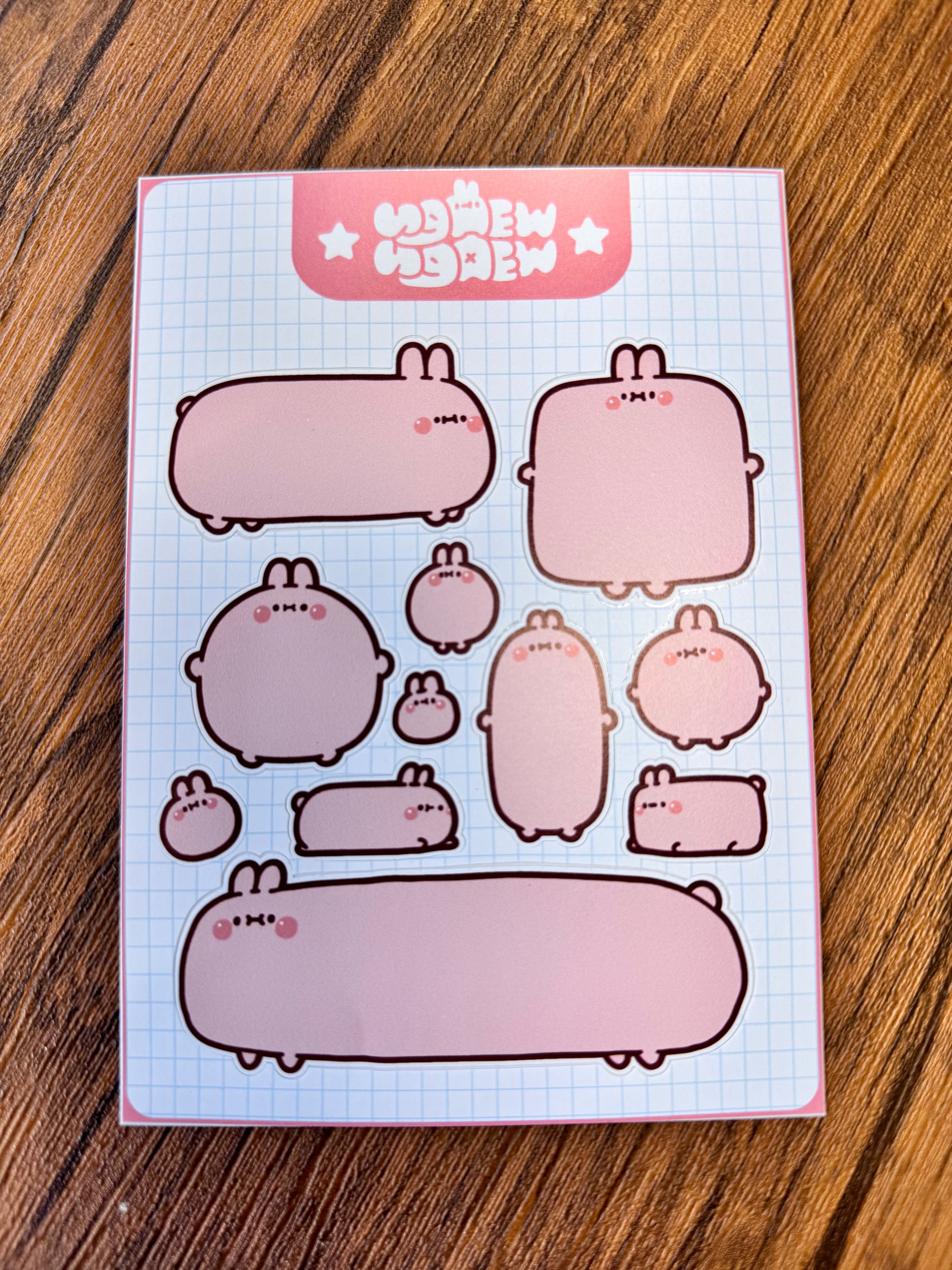 Ngaew Sticker Packs! Series 2 features pastel-pink cartoon bunnies on a light blue grid sheet, ideal for customizable labels or notes.