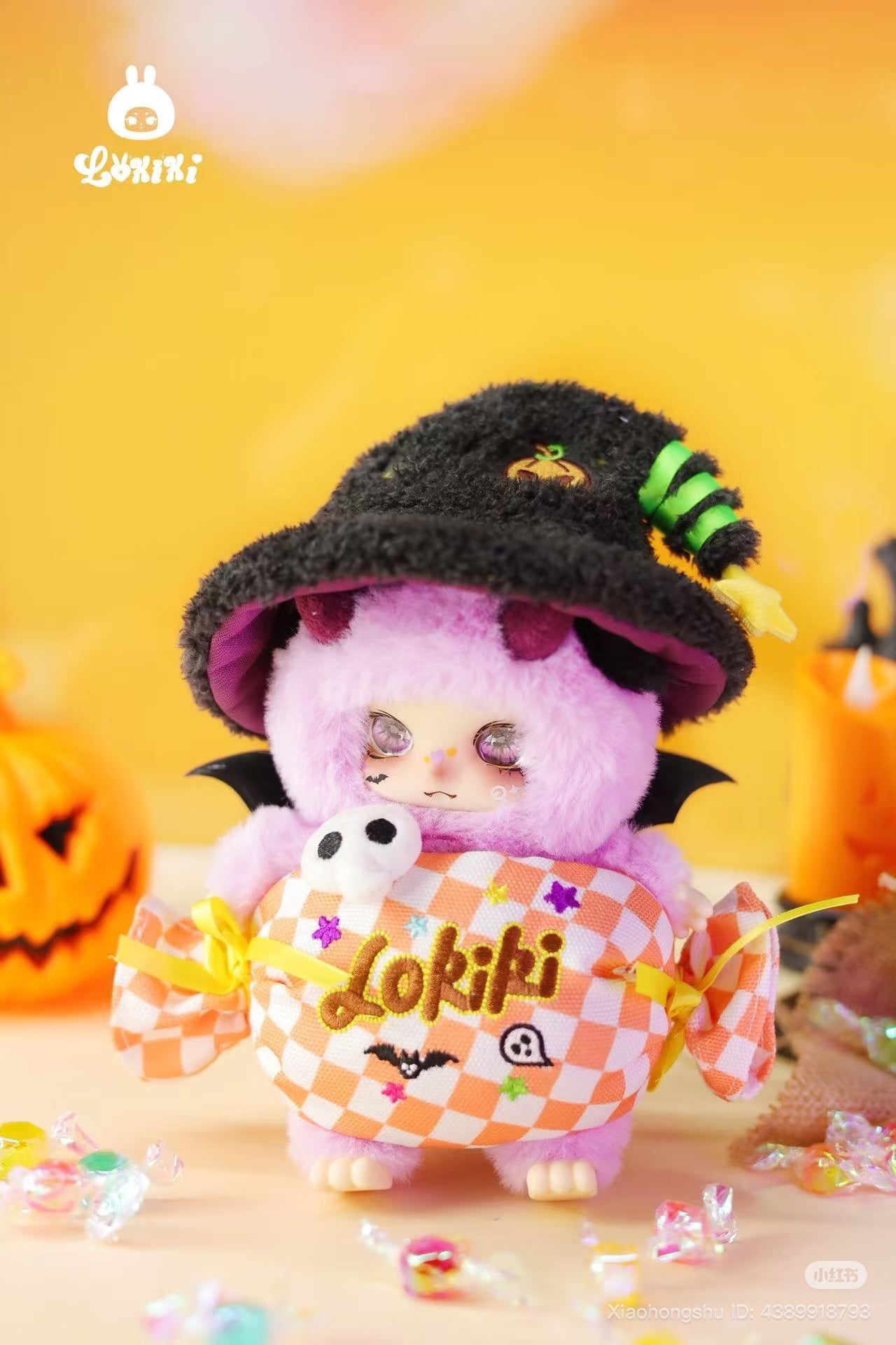 LOKKI Halloween Plush Blind Box Series: A fuzzy pink creature with horns, wings, witch's hat, and Lokiki candy cushion, set in a playful Halloween display.
