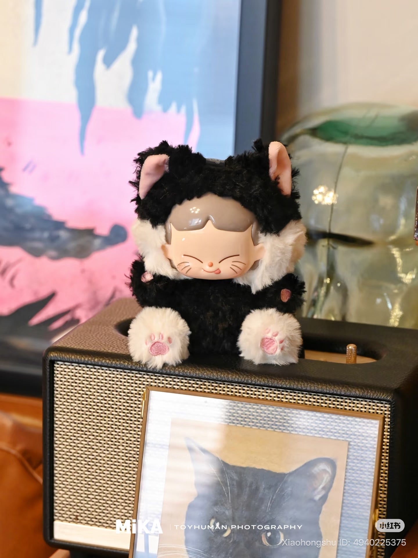 MiKA-Cat Cafe In Operation Series Plush Blind Box toy in cat suit on speaker with cat illustration, pastel painting, and glass object. Preorder for October 2025.