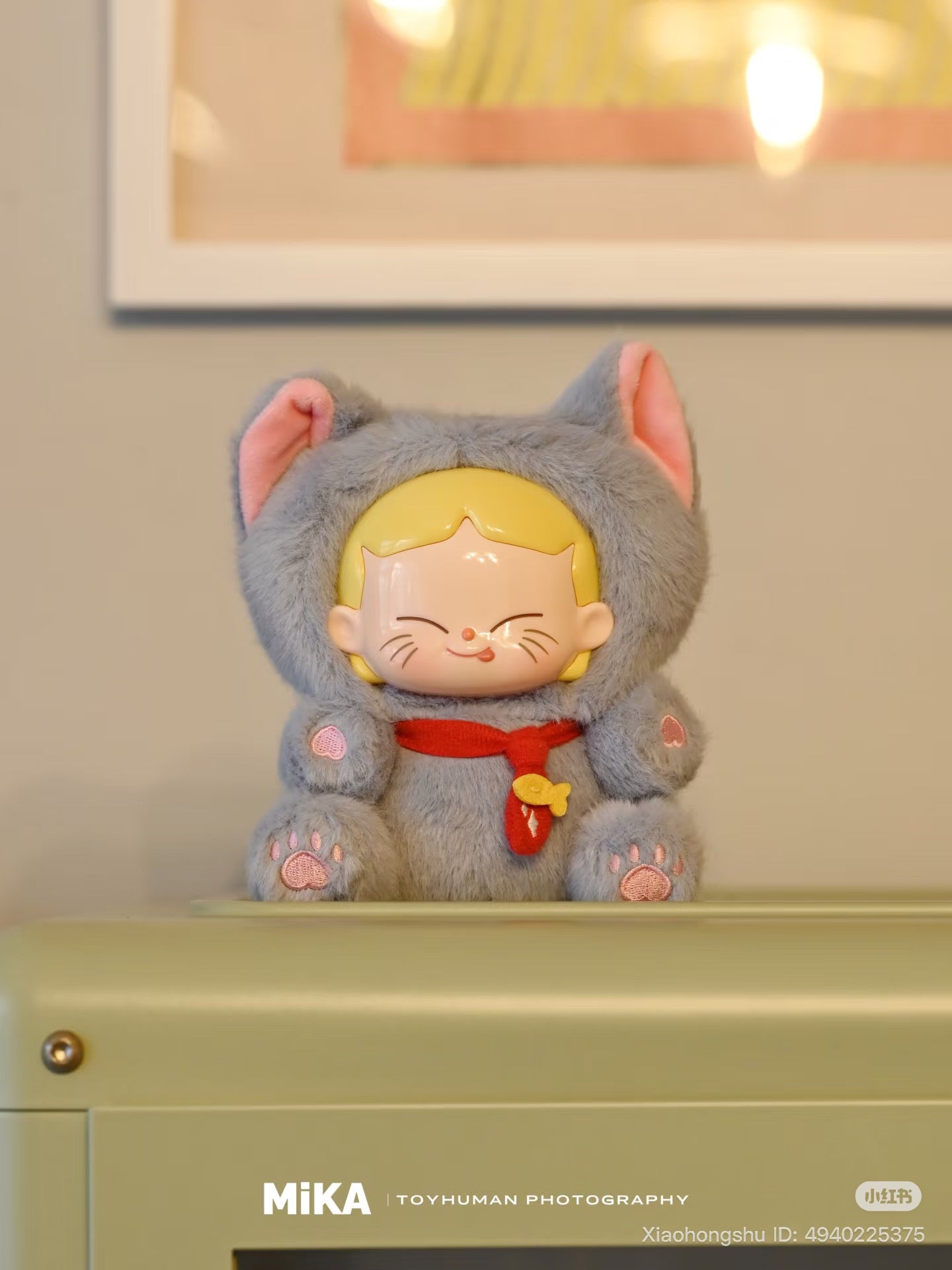 MiKA-Cat Cafe In Operation Series Plush Blind Box figurine in grey cat costume with red scarf, seated on a cabinet, featuring soft fur and painted face.
