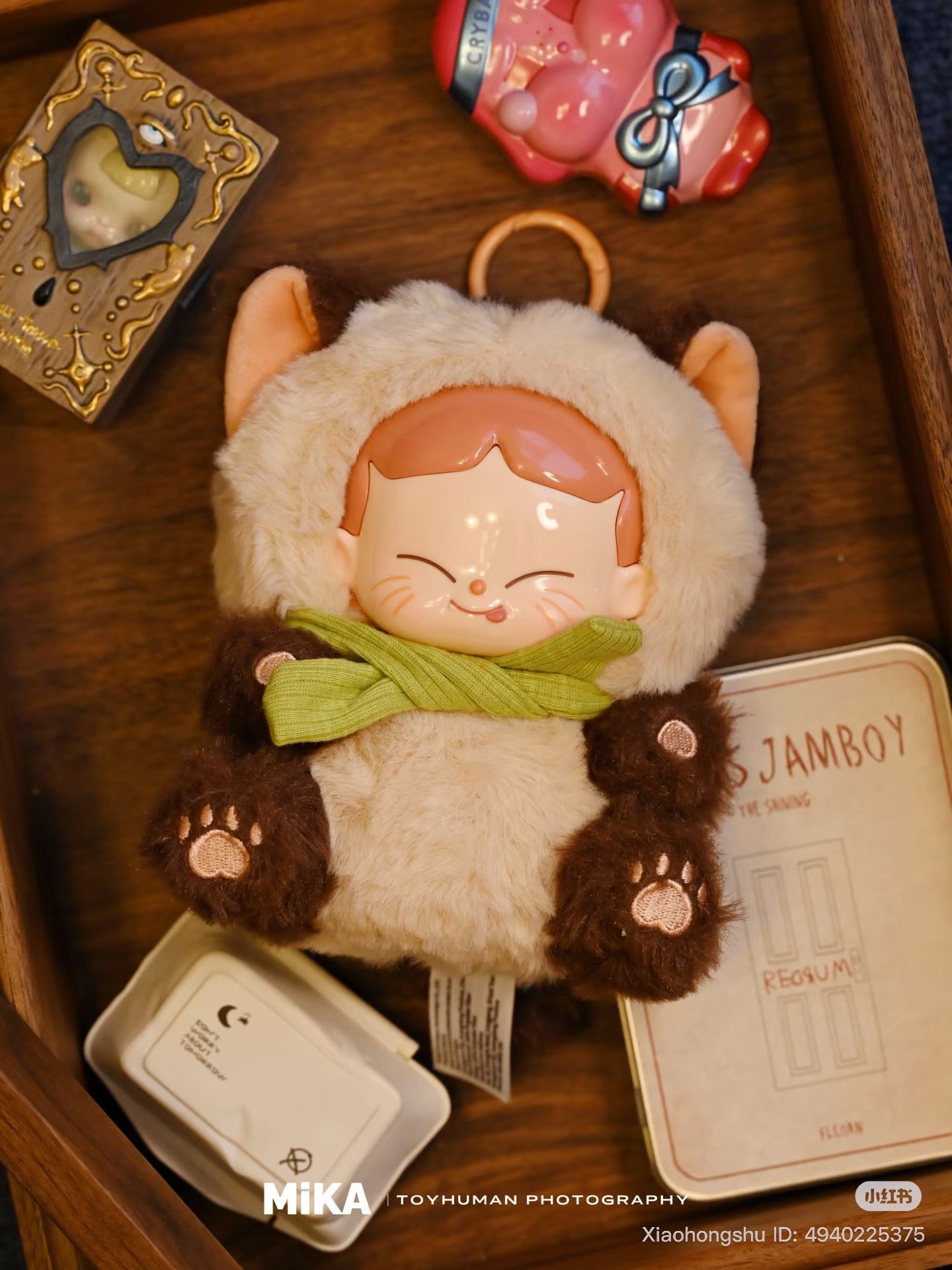 MiKA-Cat Cafe In Operation Series Plush Blind Box with a fuzzy cat-eared key-ring plush, surrounded by designer toy trinkets and collectible packaging.