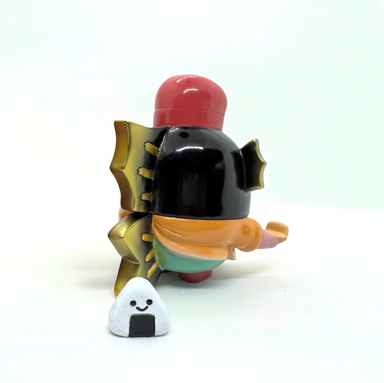 TAI EBISU (BLACK) by Teresa Chiba, a designer vinyl toy with a glossy black head and colorful body, accompanied by a small smiling onigiri figure.