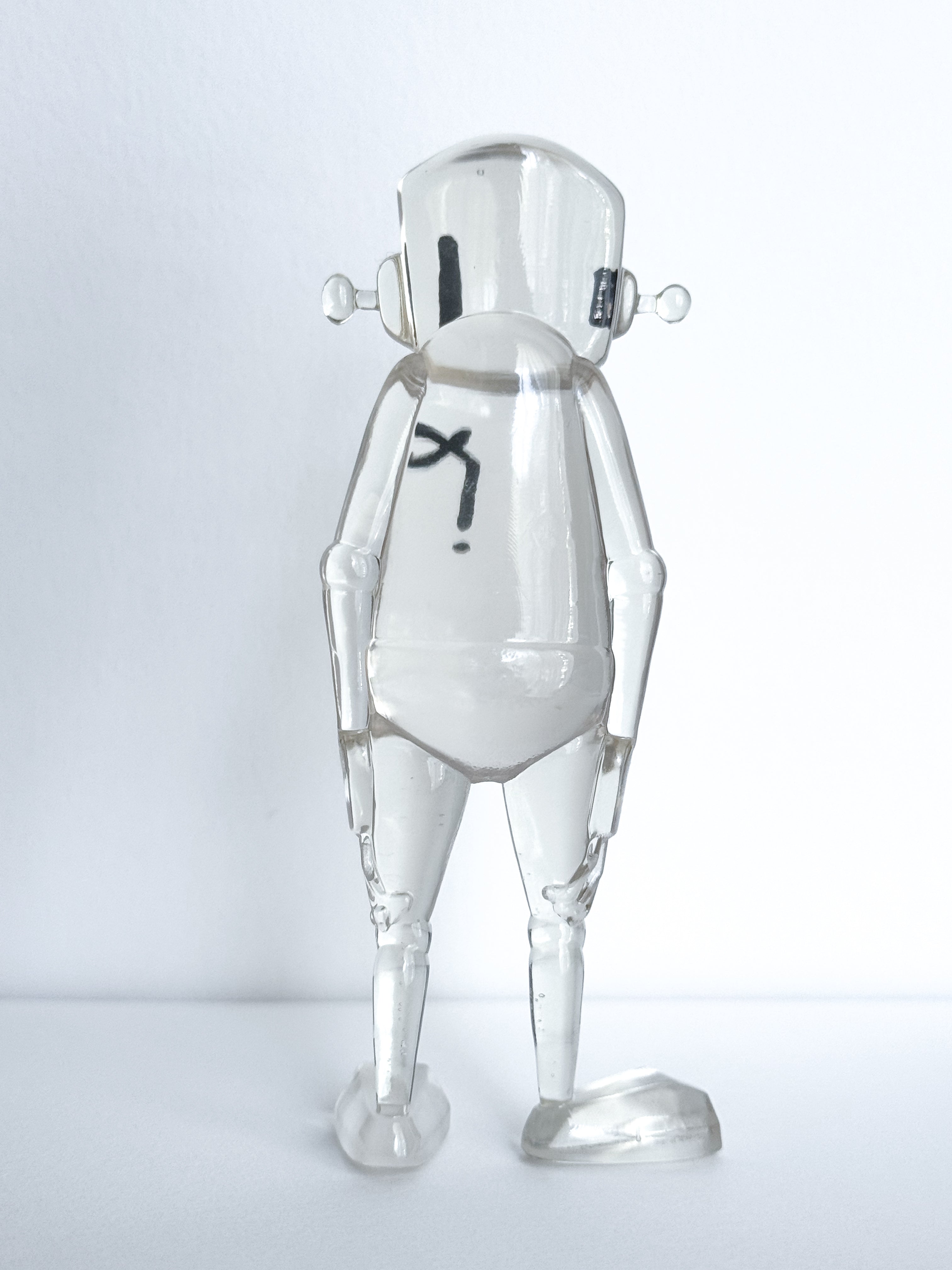 A small resin humanoid figure, Time Will Tell - Thinking Clearly by Chris RWK, features jointed limbs and a helmet-style head, resting one foot on a block.