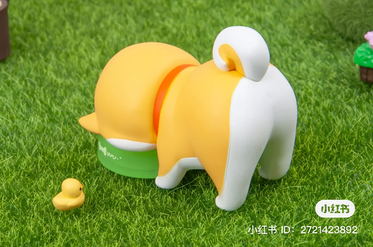 A Shiba Inu GouQi Blind Box Series toy animal on grass, part of Strangecat Toys' blind box collection. Preorder now for June 2024.