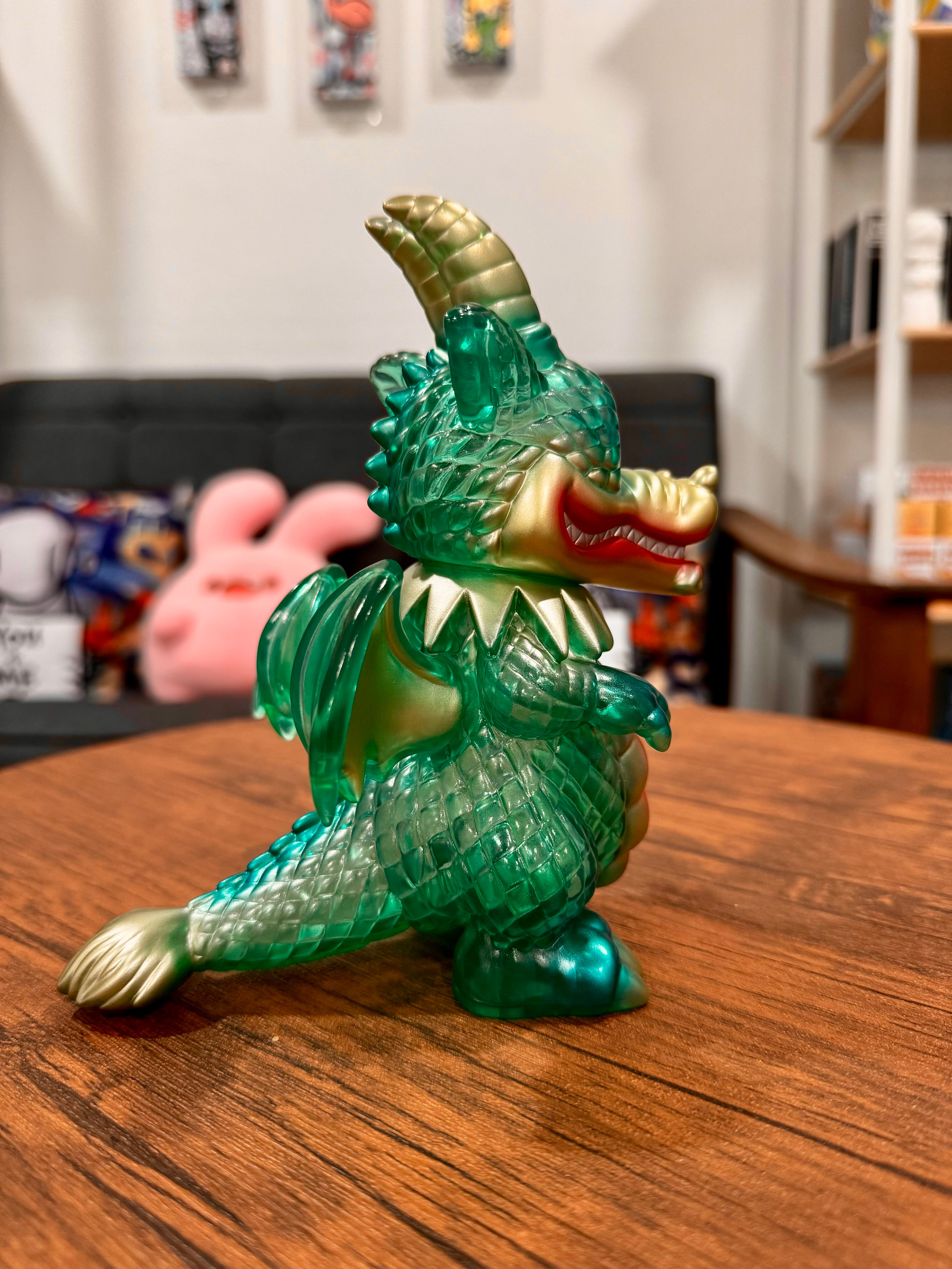 A green and gold dragon figurine, Calm Dragon Clear Mint by Art Junkie, displayed on a table. From Strangecat Toys, a blind box and art toy store.