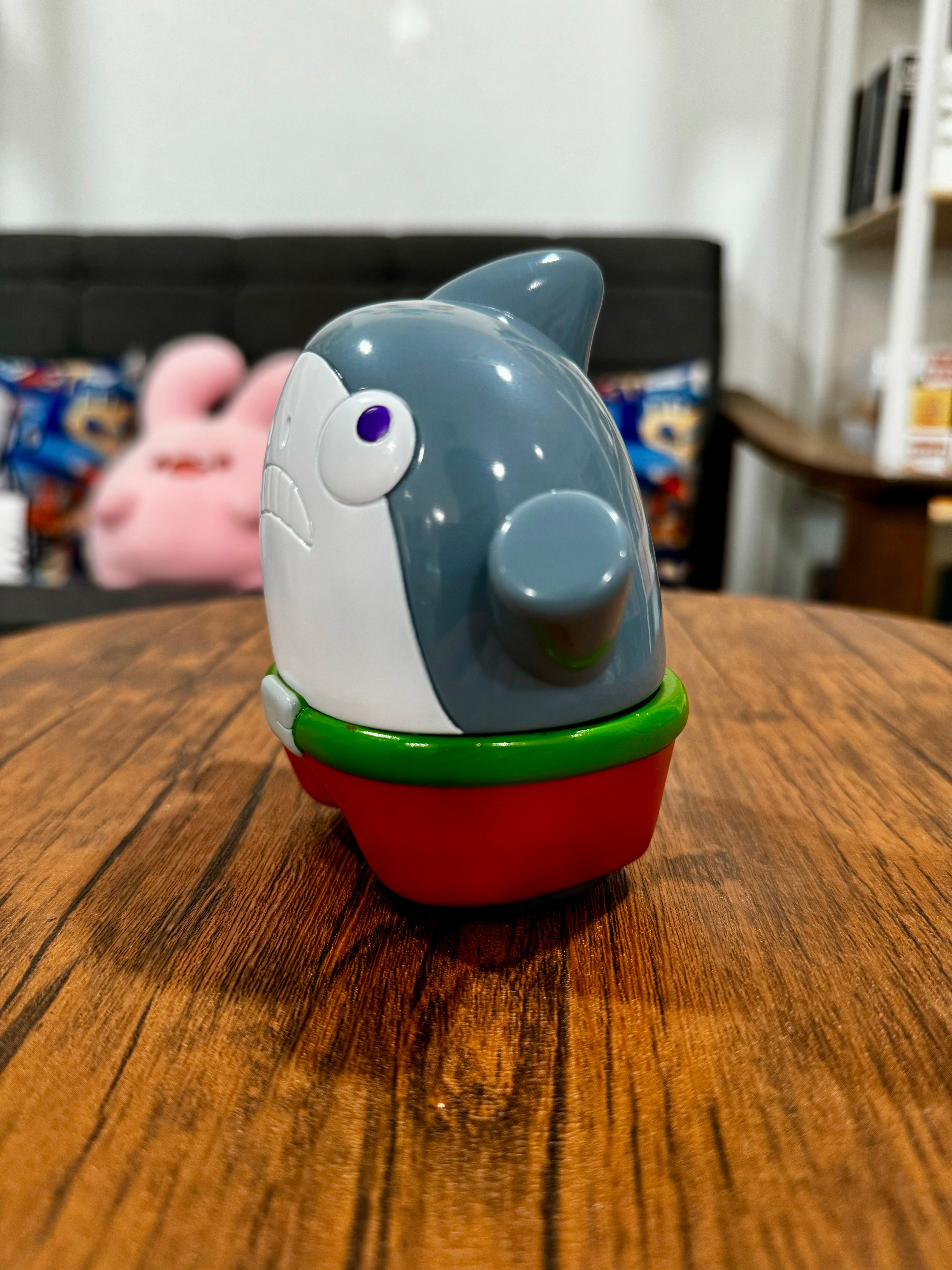 A Sofubi toy featuring SHARK Original design by CO2, 11.5cm size, on a table. Indoor, animal figure, wooden elements visible. From Strangecat Toys, a blind box and art toy store.