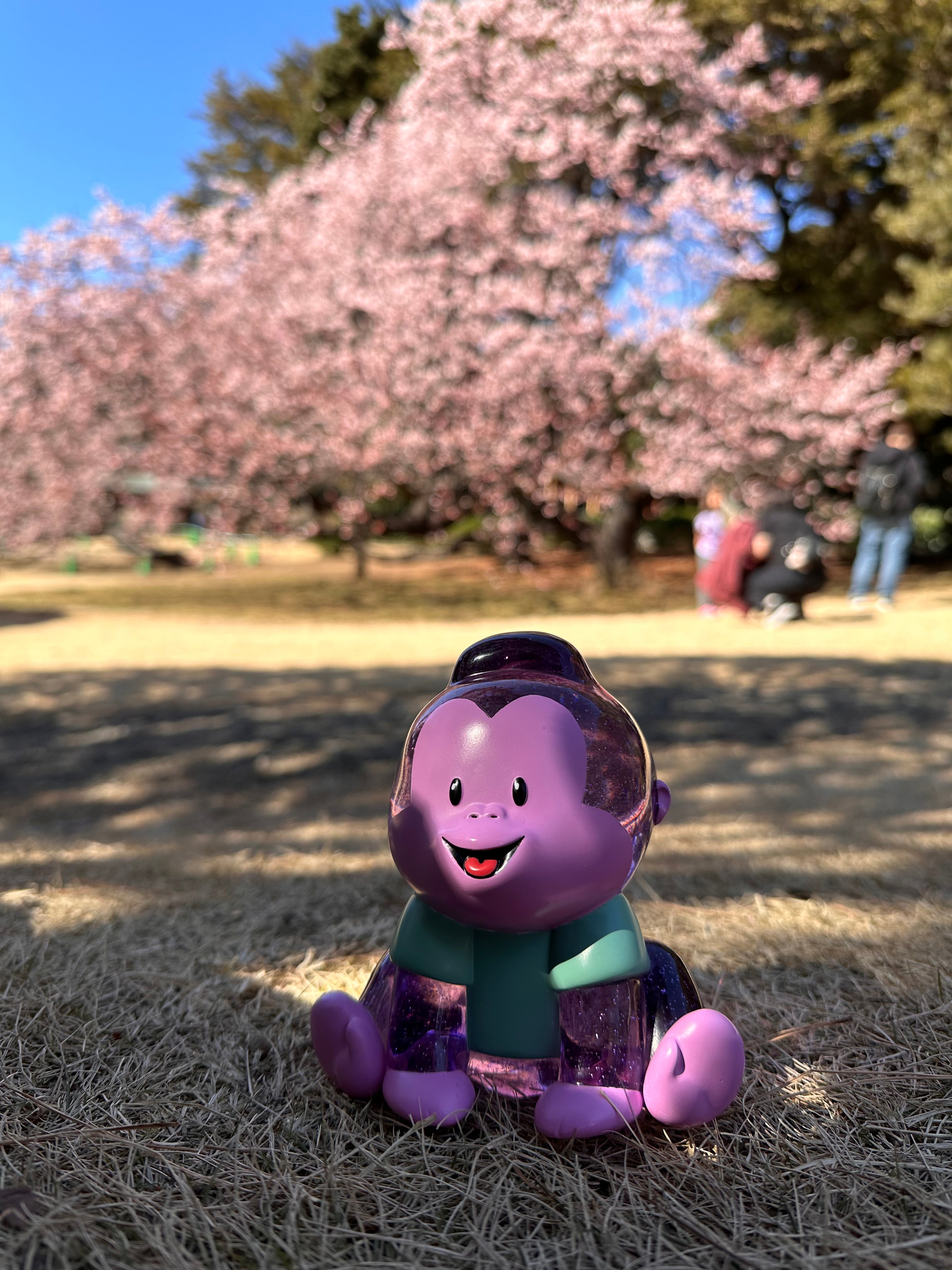Arlo by Prime purple toy monkey figurine, 5 inches tall, made of high grade resin, limited to 50pcs, outdoor setting with tree and grass.