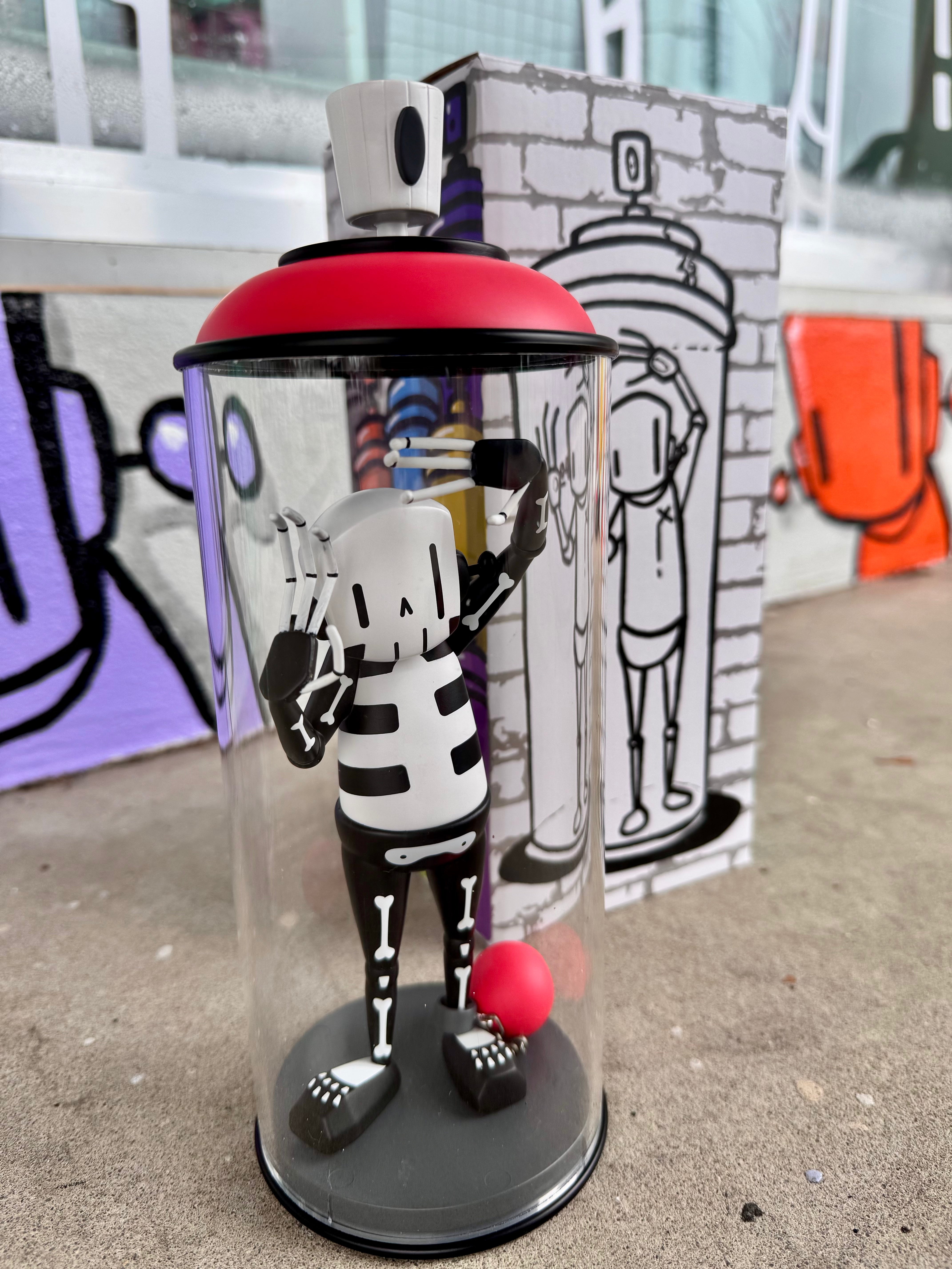 Contents Under Pressure Vinyl Figure - Bones Edition by Chris RWK, featuring a black-and-white skeleton inside a spray-can-shaped acrylic display, with matching graffiti-themed box art.