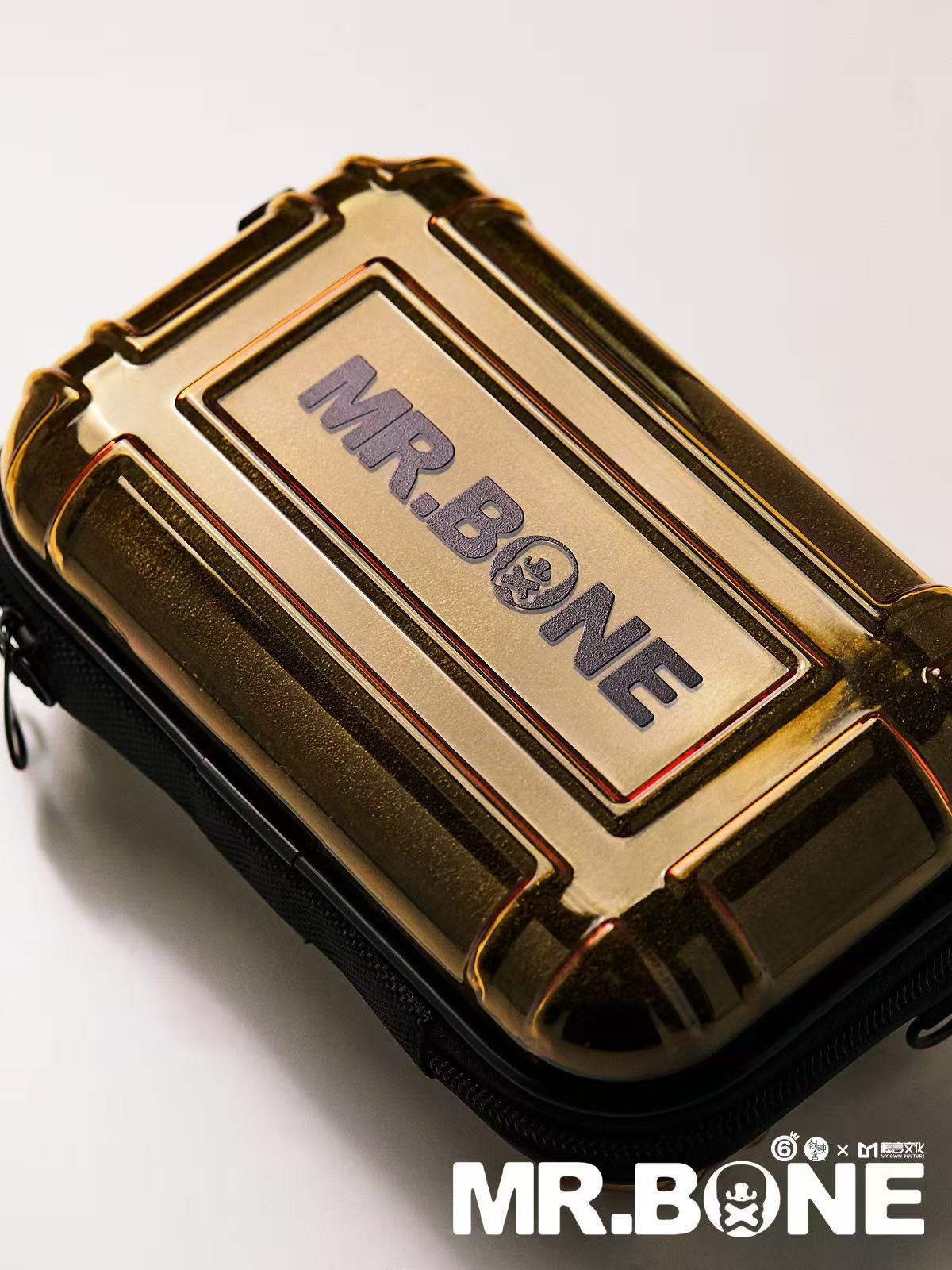 Mr Bone Yakuza Limited Set 100% - Preorder features a gold hard-shell case with embossed branding, ideal for gadget protection, including a dog figurine.