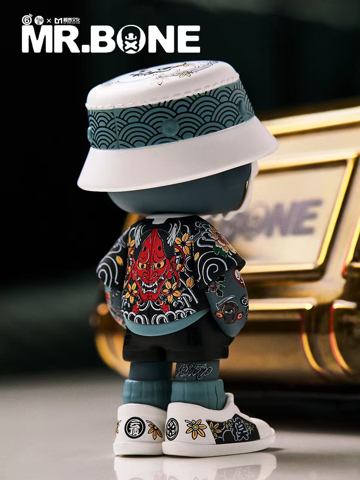 Mr Bone Yakuza Limited Set 100% features a vinyl figure in streetwear with Japanese motifs, including a seigaiha bucket hat and oni mask jacket. Preorder includes a dog and case.