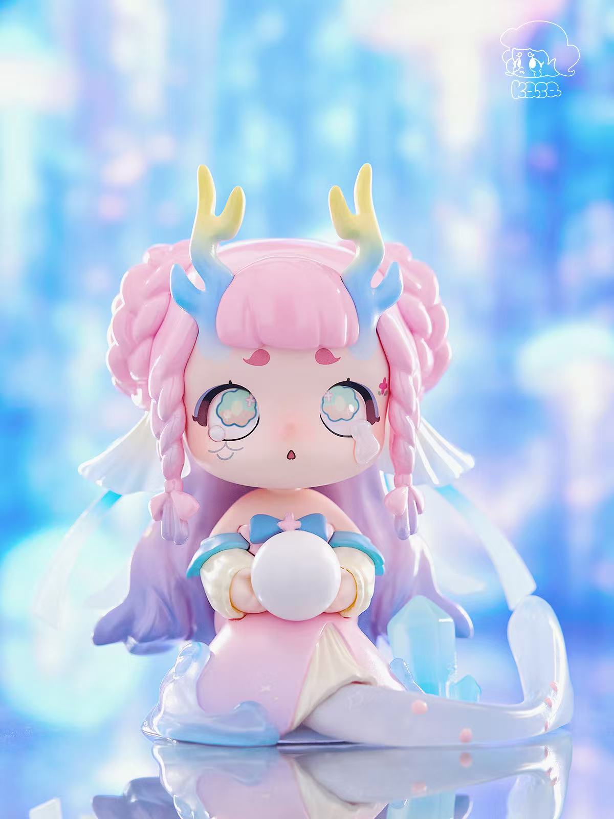 KASA 2.0 - Mystic Tales Blind Box Series: Chibi figure with pink braids, antlers, holding an orb amid translucent waves and crystals, creating an ethereal scene.