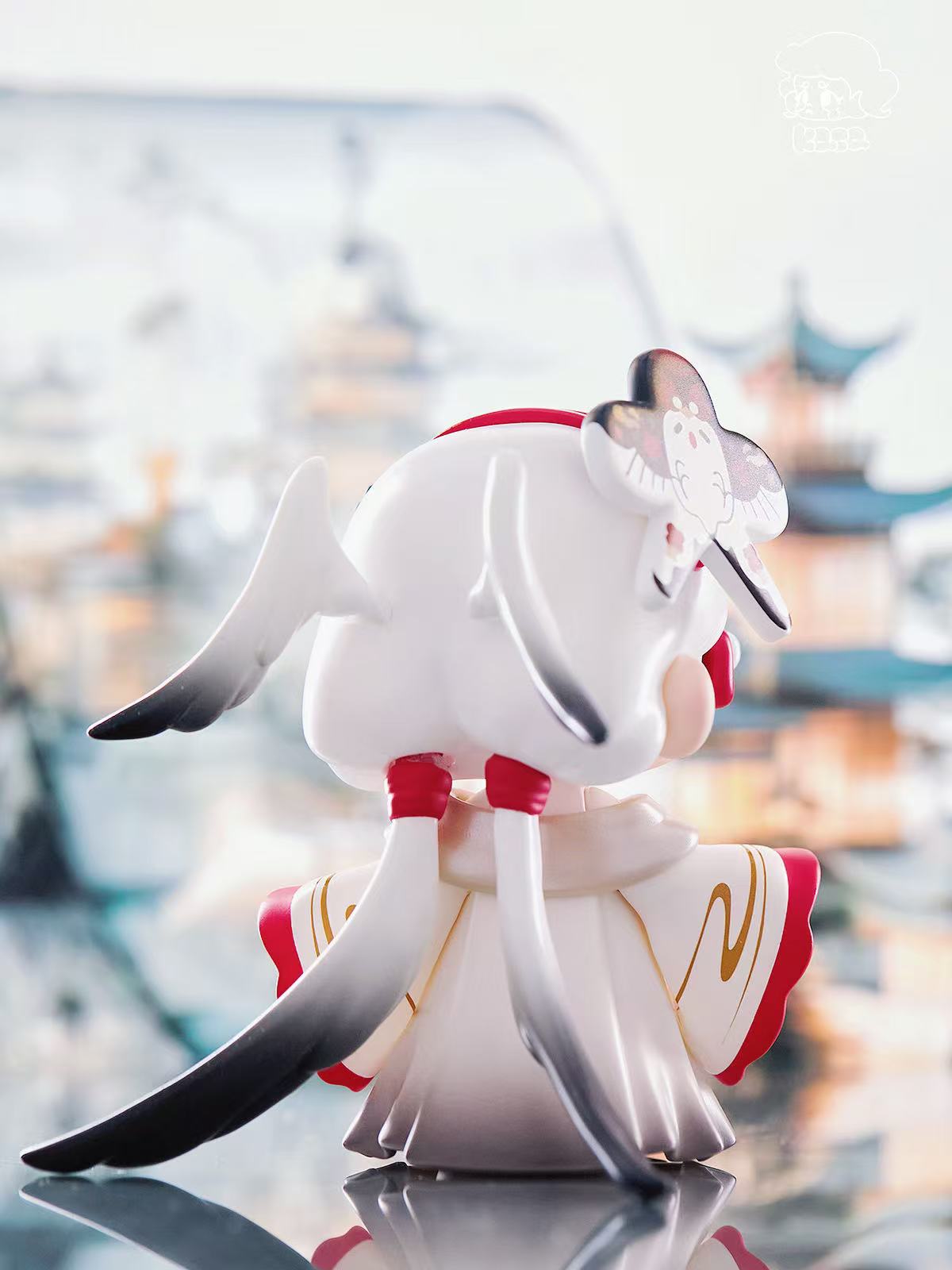 KASA 2.0 figurine in a traditional robe with wing-like headdress and bird ornament, set against an East-Asian architectural backdrop.