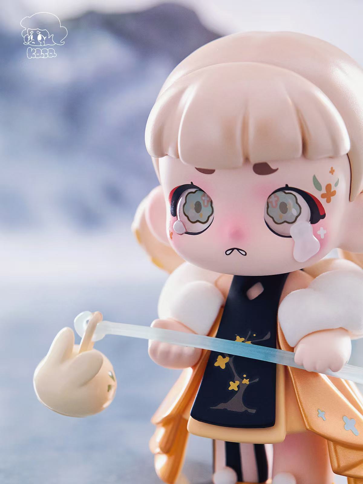 KASA 2.0 - Mystic Tales Blind Box Series: A chibi-style figure with flower eyes, blonde bob, navy-gold outfit, holding a rod with bunny charm.