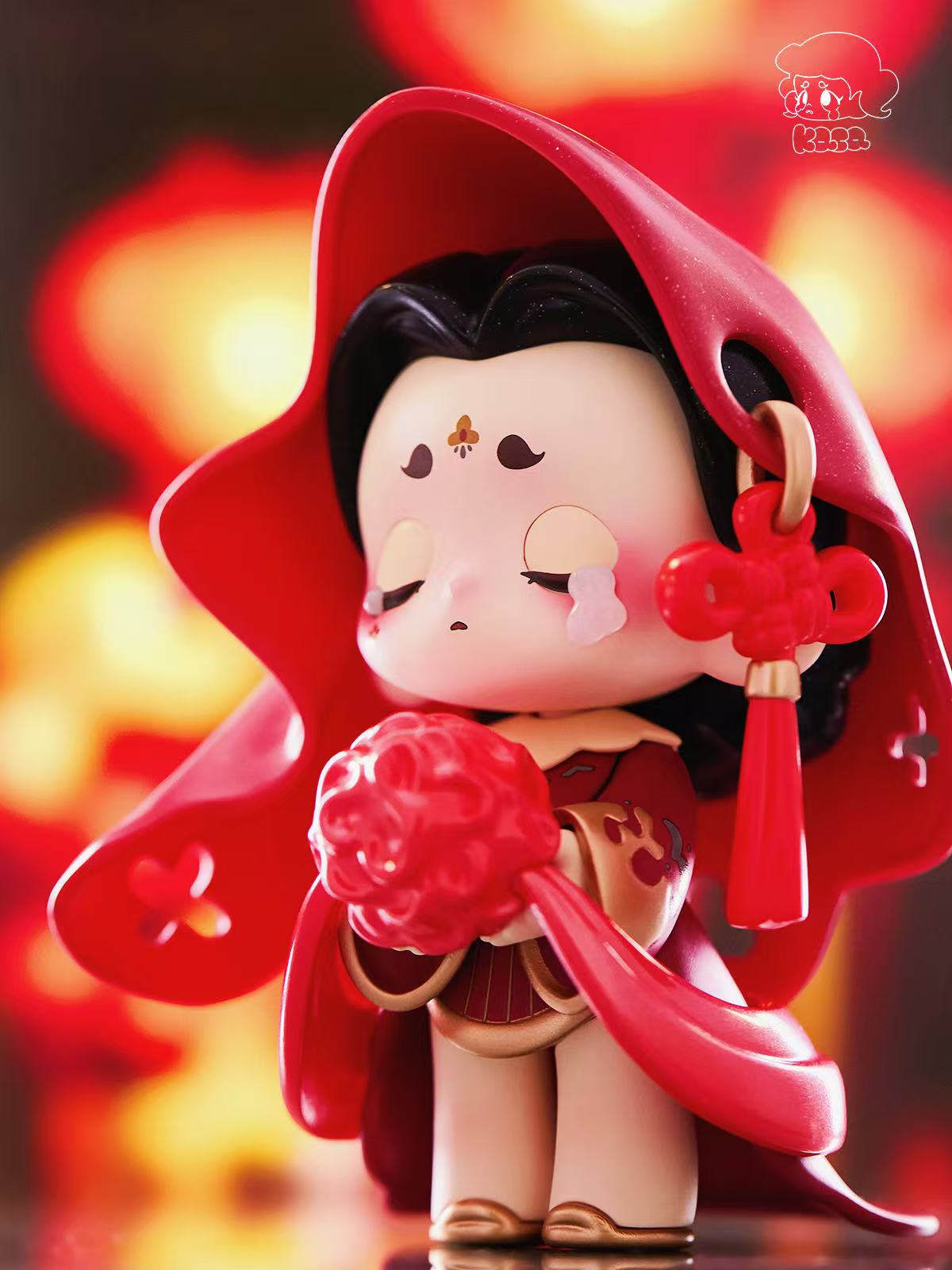 KASA 2.0 - Mystic Tales Blind Box Series figurine with scarlet cloak, red-knot earrings, floral forehead motif, and pom-pom bouquet, reflecting East Asian ceremonial dress.