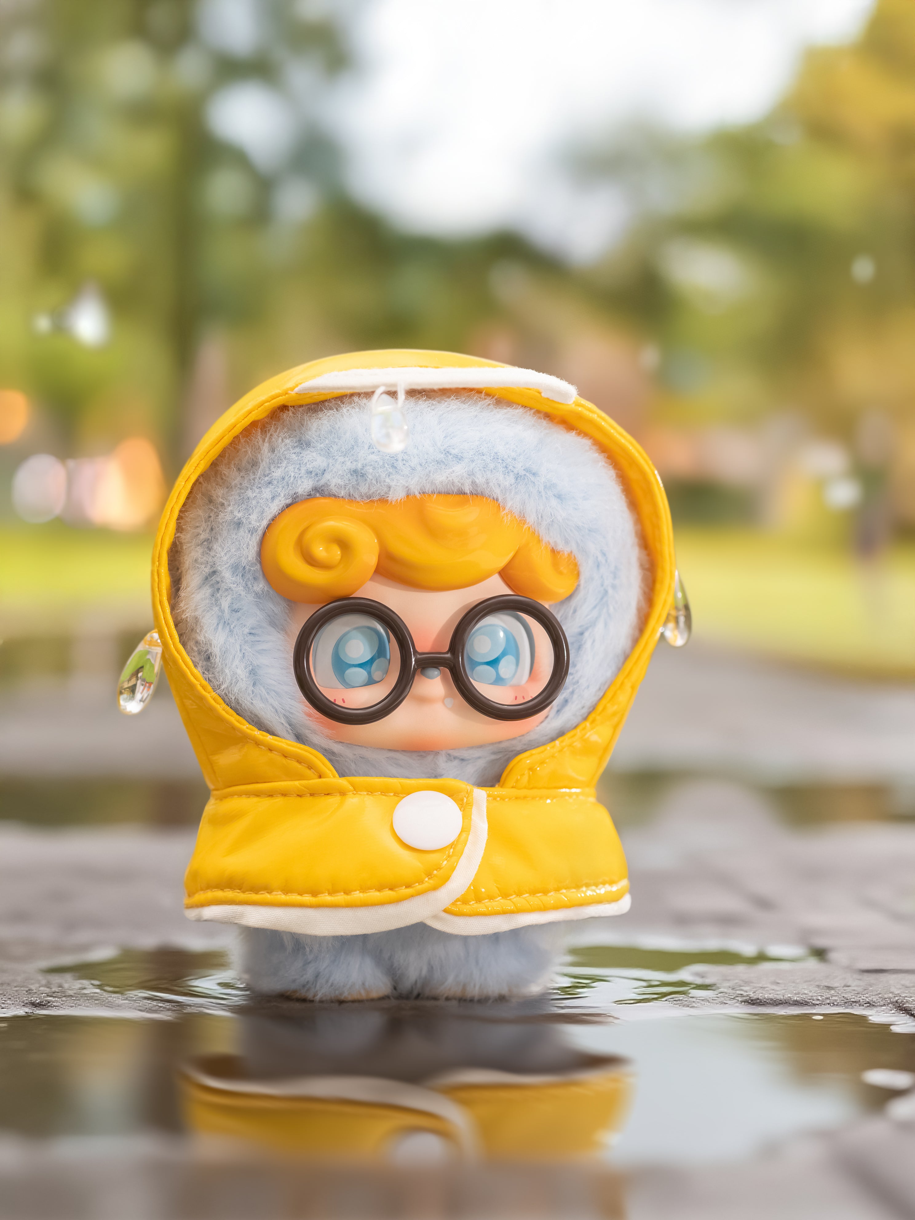 Q. Kid Outdoor Activities Series: A plush toy in a yellow raincoat, oversized glasses, standing in a puddle, reflecting Strangecat Toys' whimsical blind box offerings.
