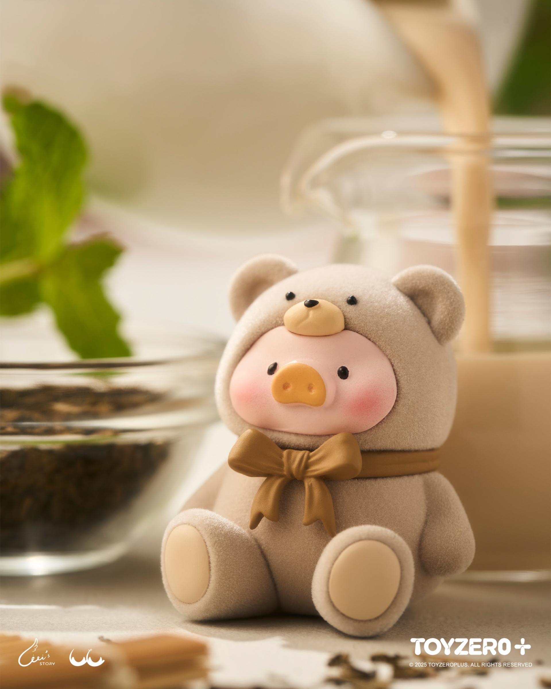 LuLu the Piggy - Teddy MINI Limited Edition in a bear onesie, surrounded by a tea-time setup, emphasizing its collectible charm. Preorder from Strangecat Toys.