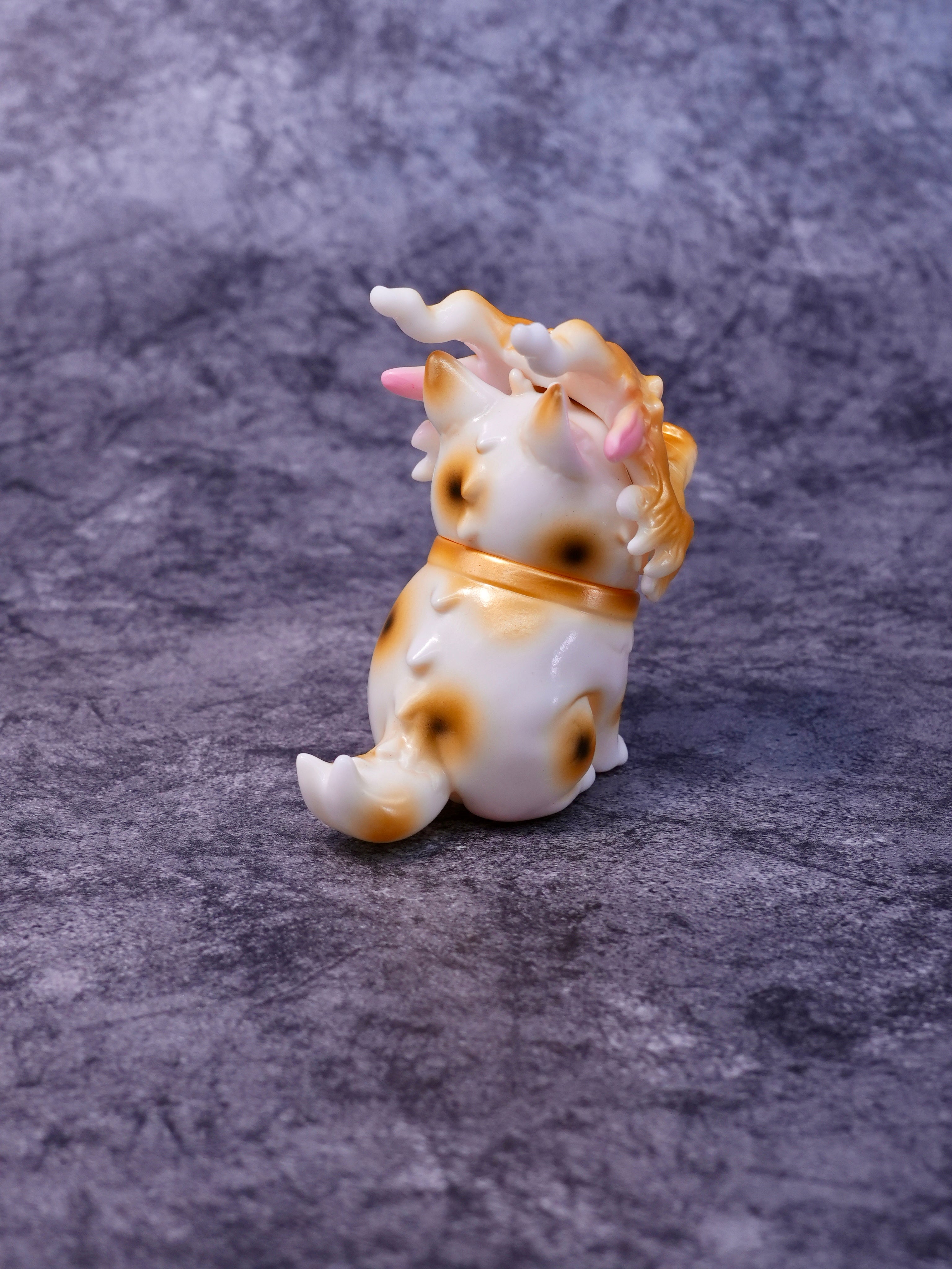 Lucky Loong cat by HOTRU, a 6.5cm glossy white vinyl figurine with golden-brown spots, featuring pink accents, horns, and a curled tail. Preorder now.