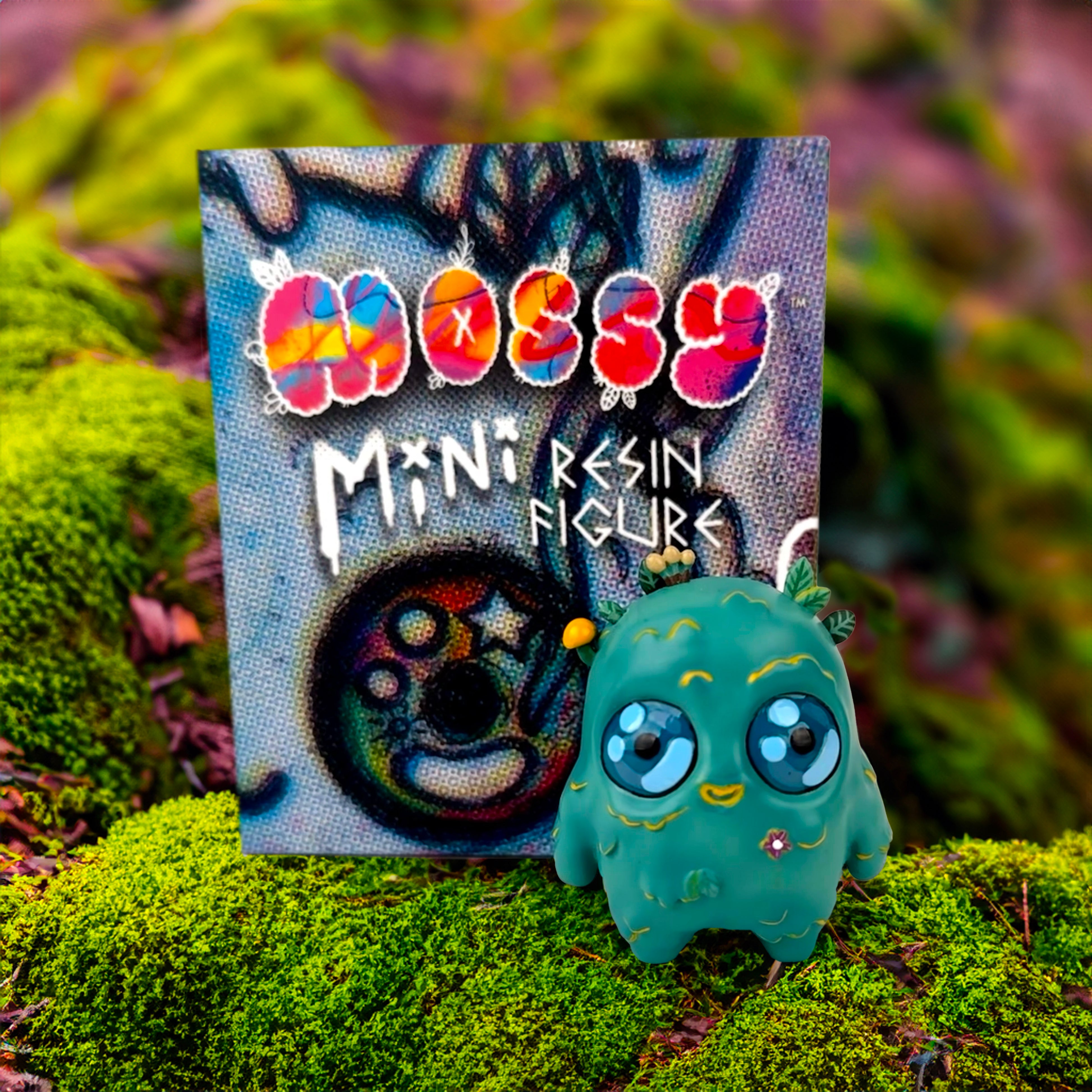 Mossy - The Mini Moss Spirit by Mumbot, a small resin toy depicting a forest spirit, sits on moss, emphasizing its whimsical and artistic design.
