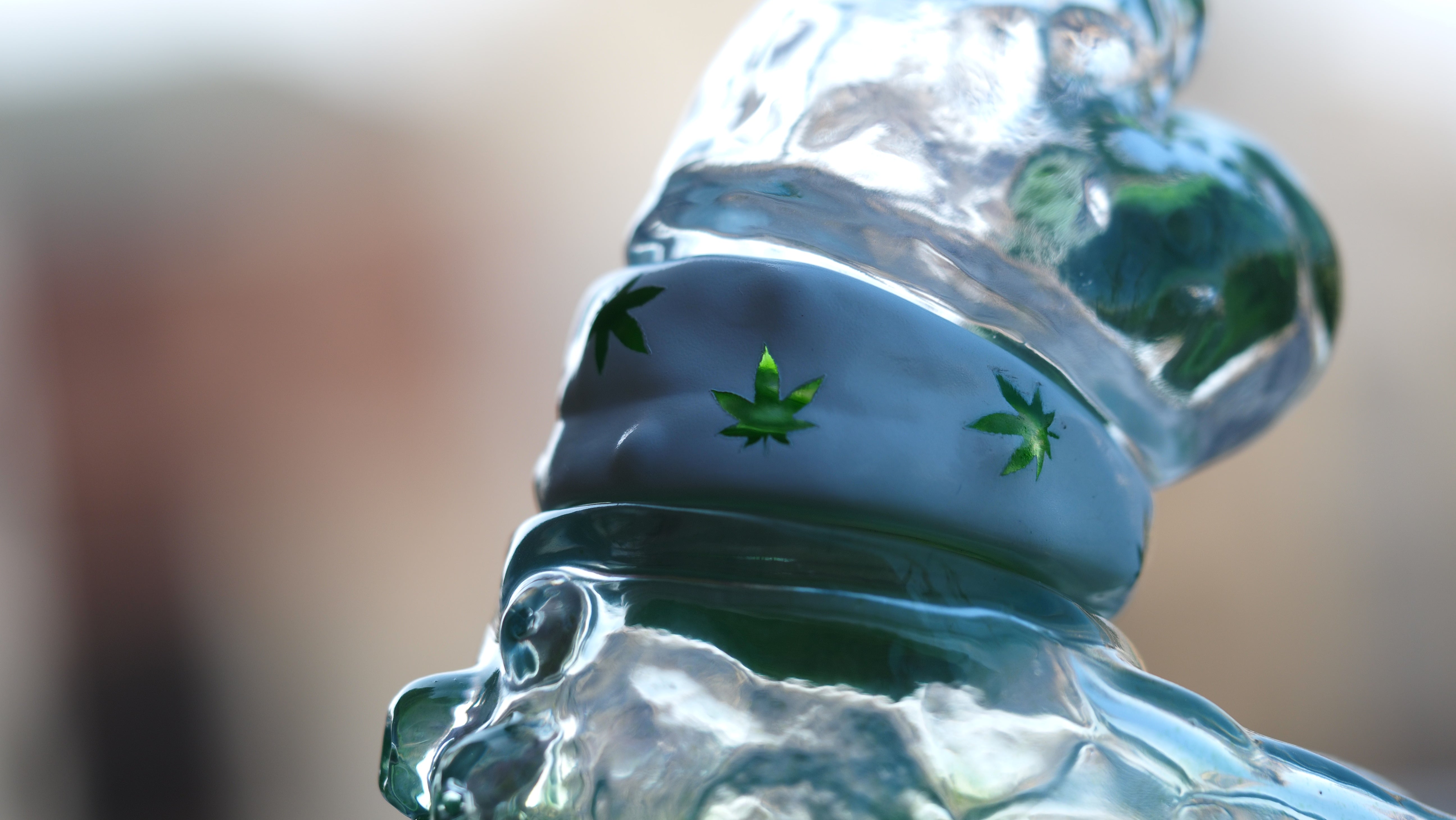 A close-up of BONG A-MON, a 9 cm tall sofubi/resin figure with a glass-like texture. Features a green leaf motif. Preorder - Ships Late May 2024.