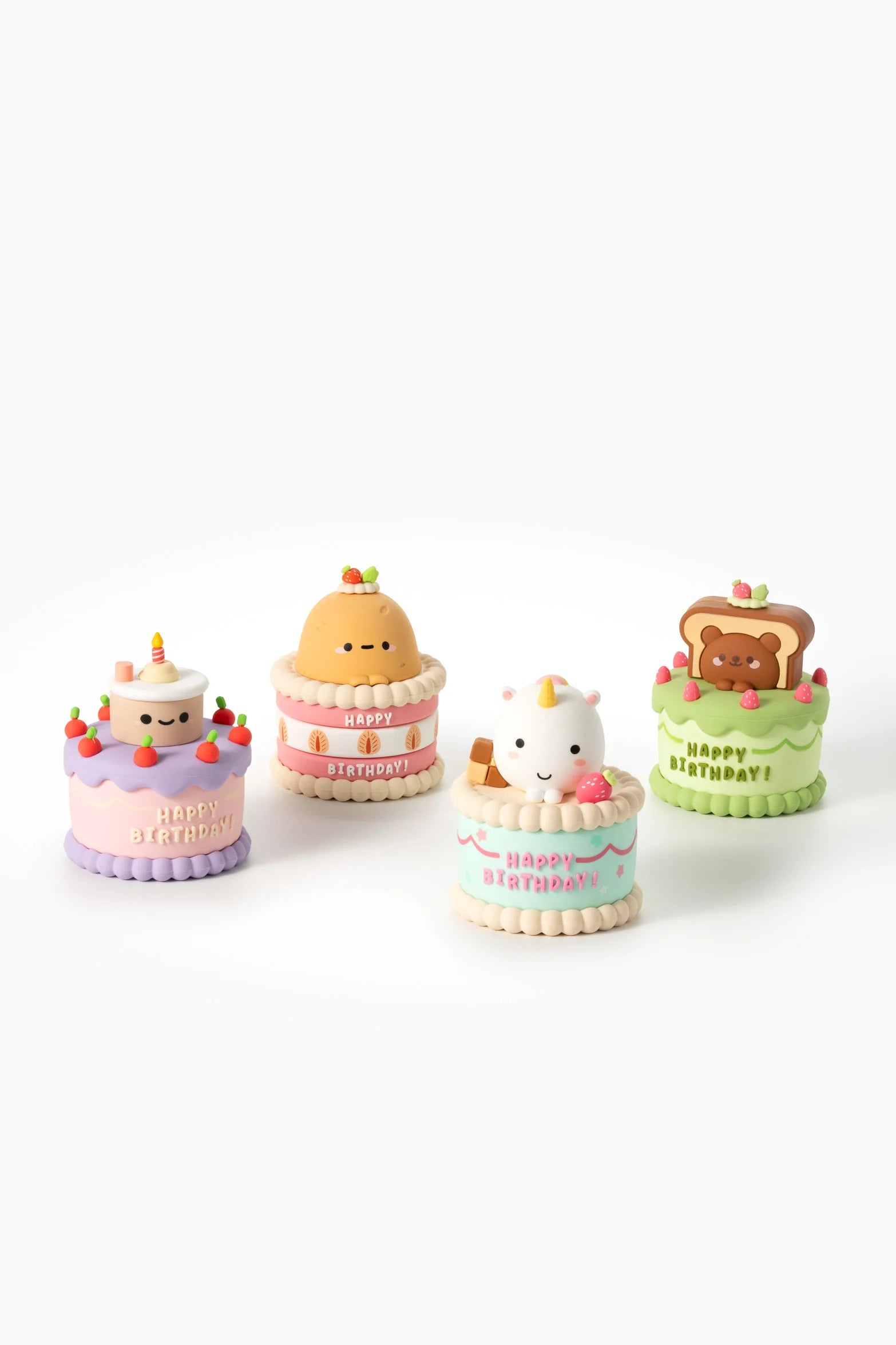 Smoko Friends Birthday Cake Blind Box Figure featuring four pastel, kawaii cake figurines with characters: smiling cake, pudding, unicorn, and bear. Collectible art toy.