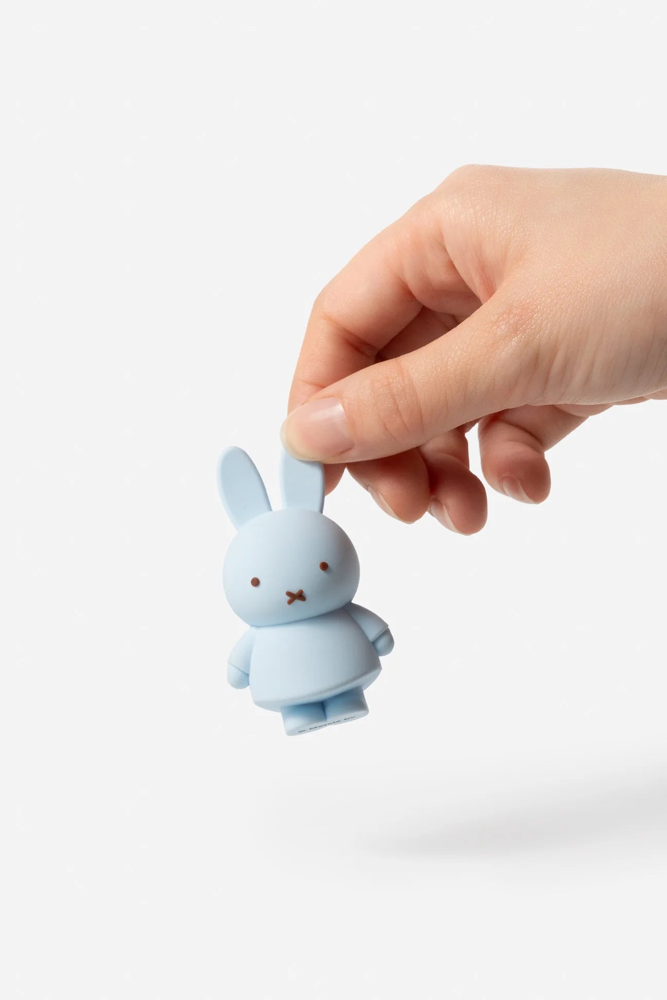 Smoko Miffy Goes Pastel Blind Box Figure in pale blue, pinched by the ear, highlighting its collectible vinyl form against a white background.