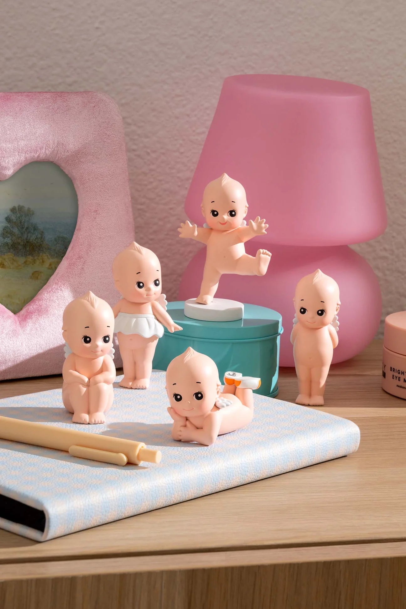 Smoko Kewpie®️ Blind Box Figure displayed on a desk with a light-blue notebook, pens, and decorative items, showcasing its collectible charm.