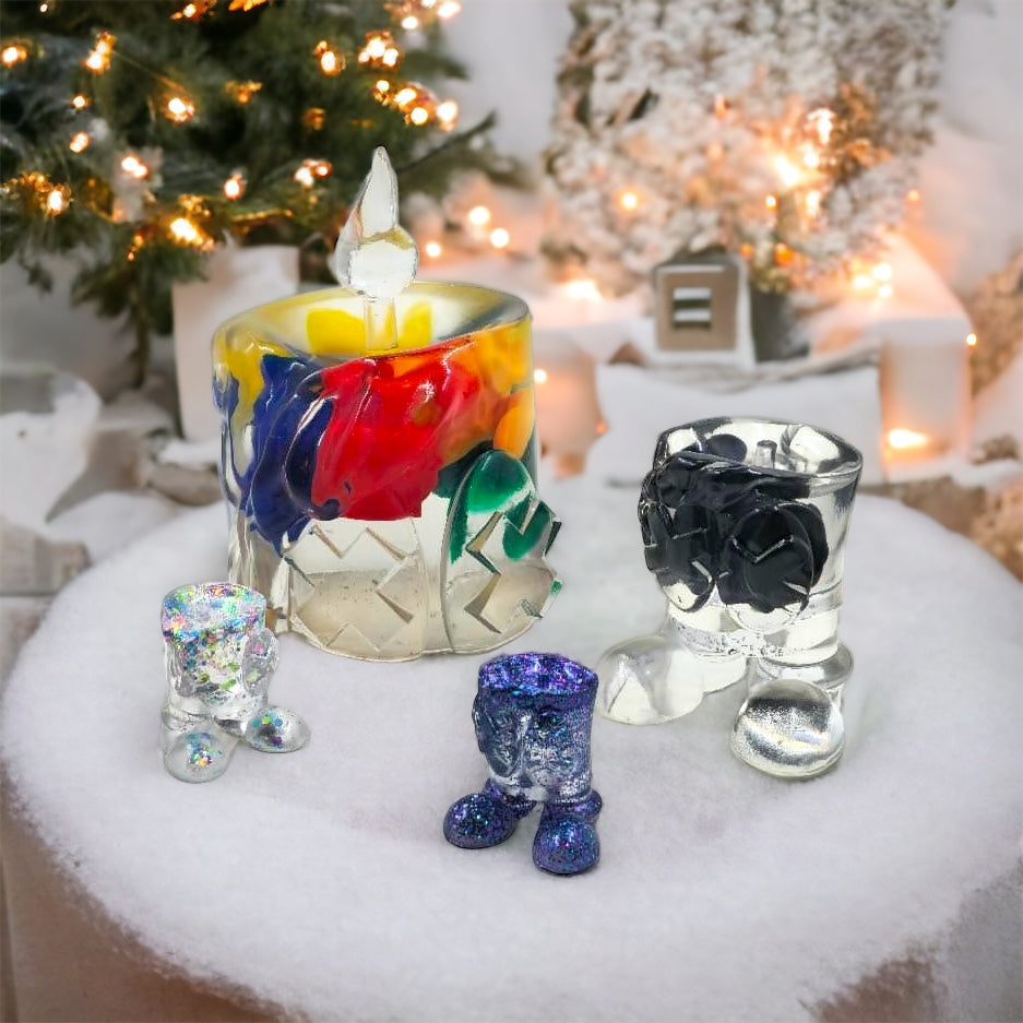 A group of glass boots and a glass vase with a colorful candle holder and candle stick.