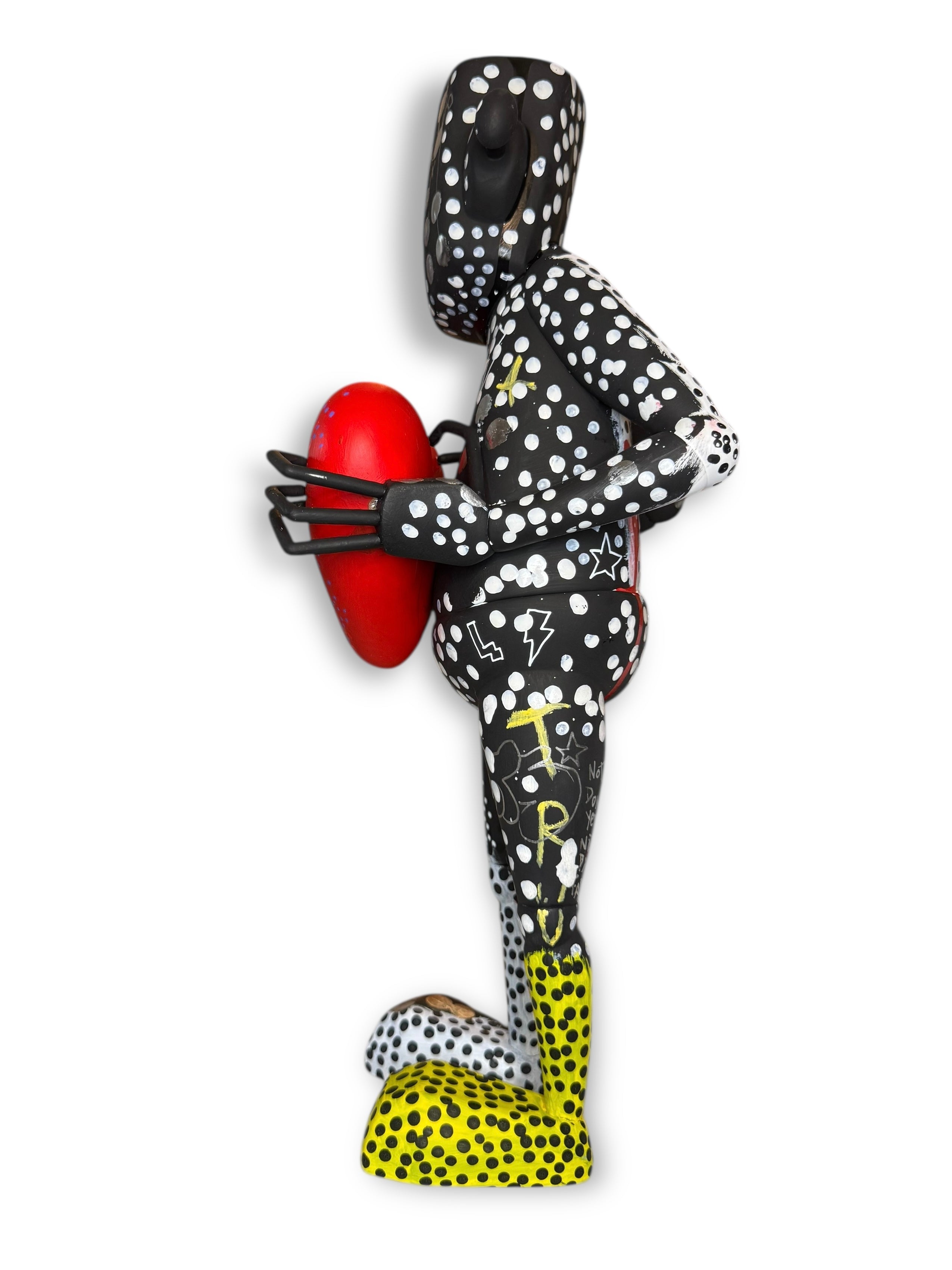 Abstract humanoid sculpture Time Will Tell - 'Pop' by Chris RWK, featuring black and white polka dots, red egg form, yellow accents, and playful graphic markings.