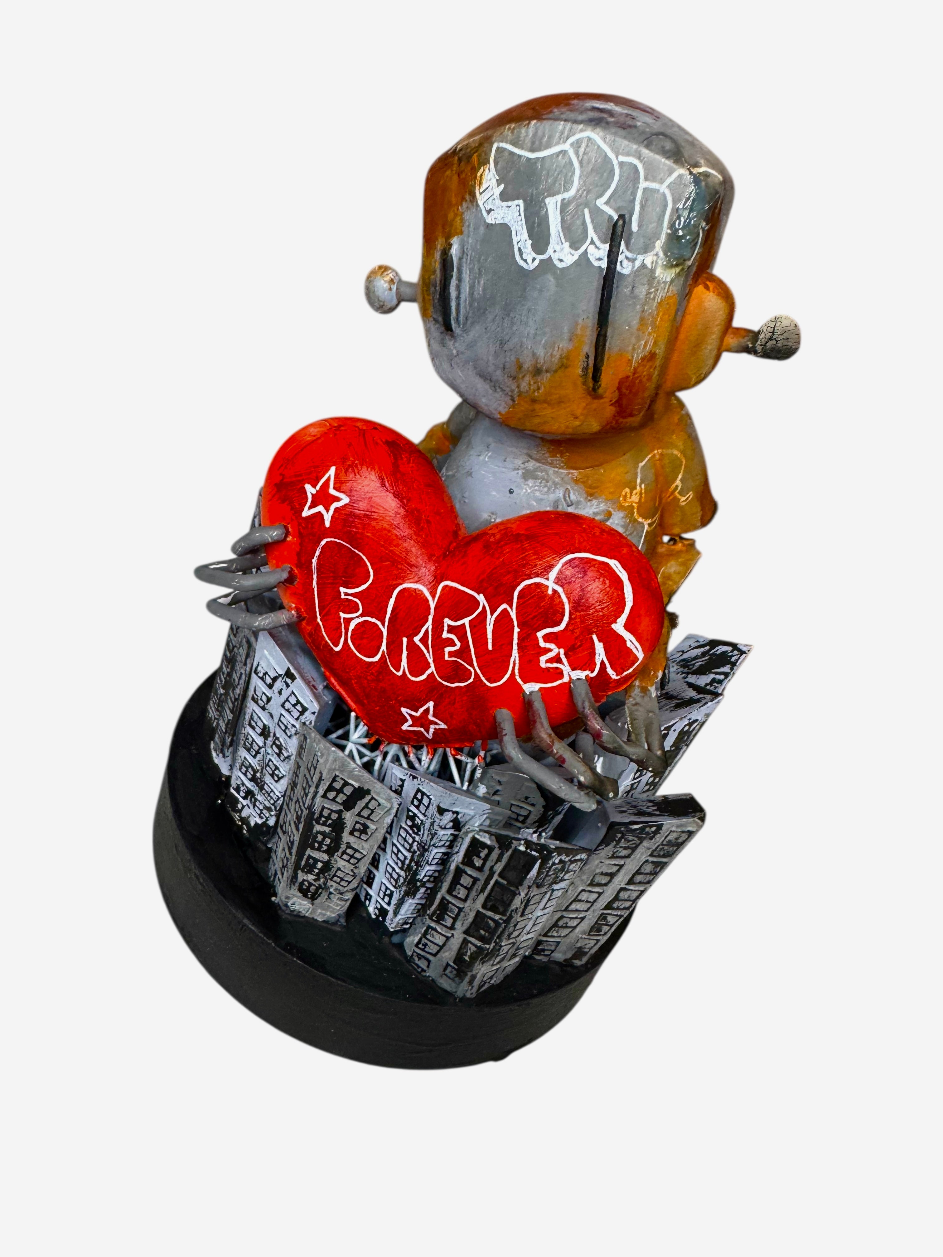 Time Will Tell - Still standing by Chris RWK: A metallic toy figure clutching a red heart with FOREVER, surrounded by a cityscape on a black base.