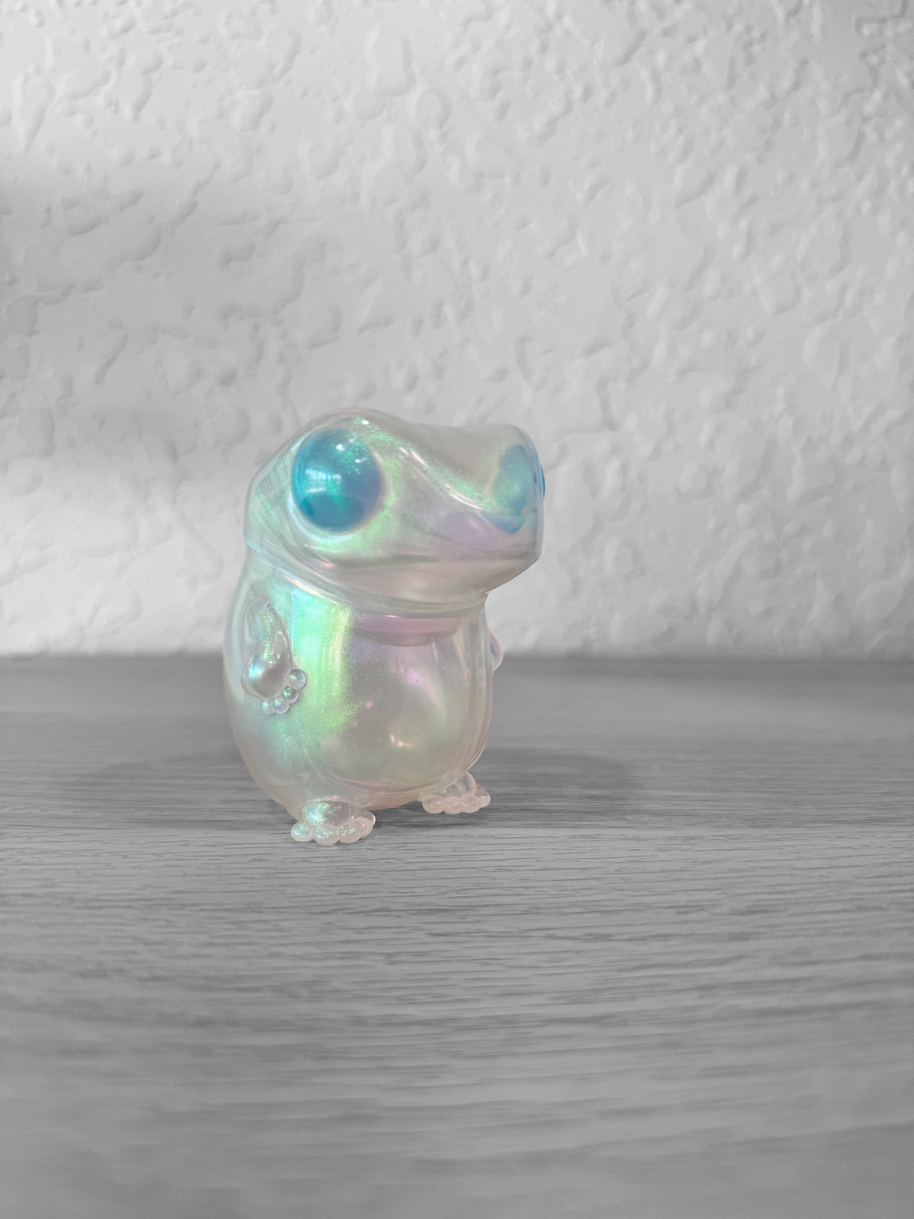 Froggy - Soap Bubble Blue by Frog Tree, a 8cm Japanese soft vinyl toy depicting a small frog, showcased on a wooden surface.