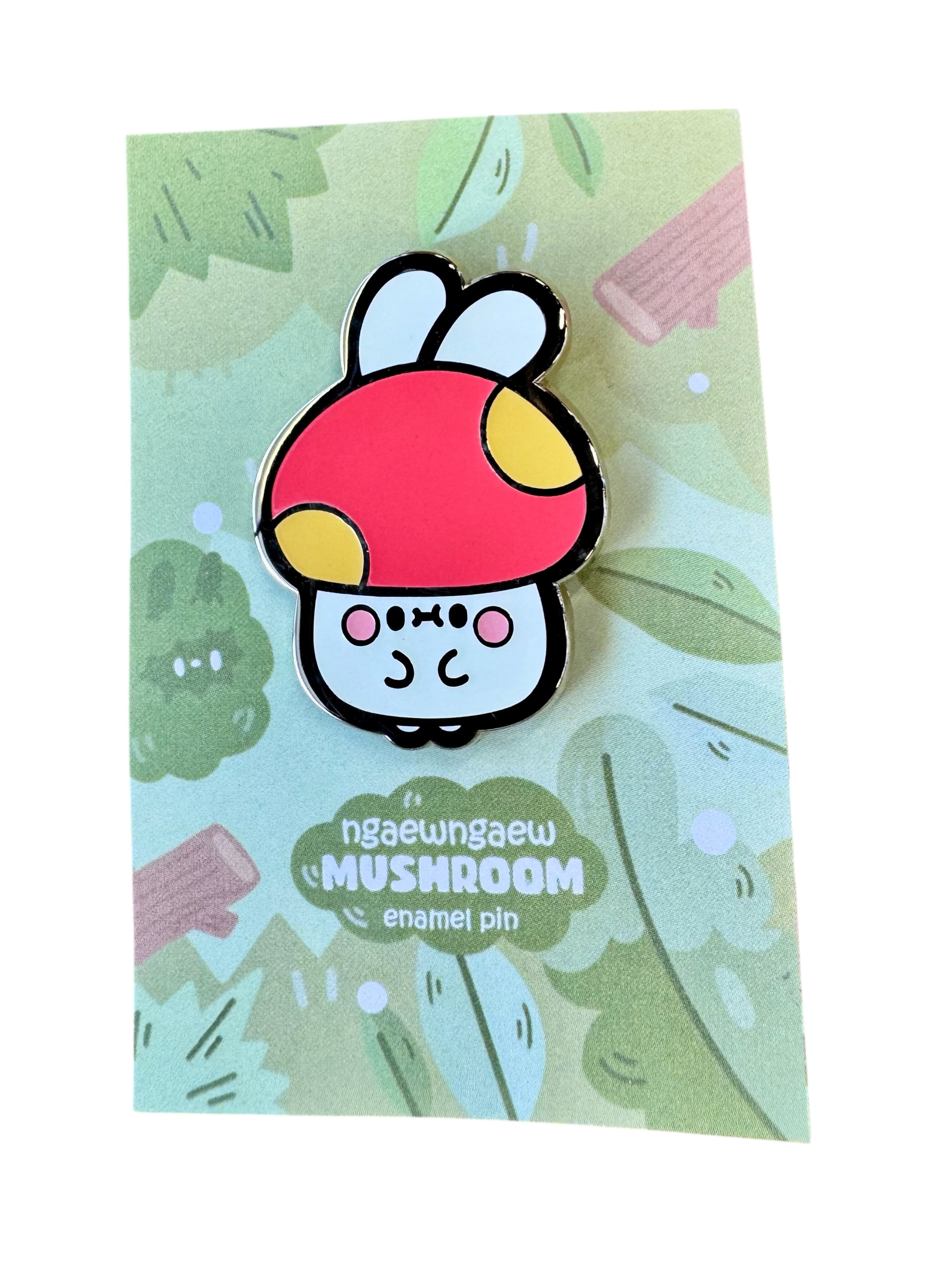Ngaew Ngaew Mushroom Pin features a whimsical mushroom character with a red cap and bunny ears, displayed on a green backing card with nature illustrations.