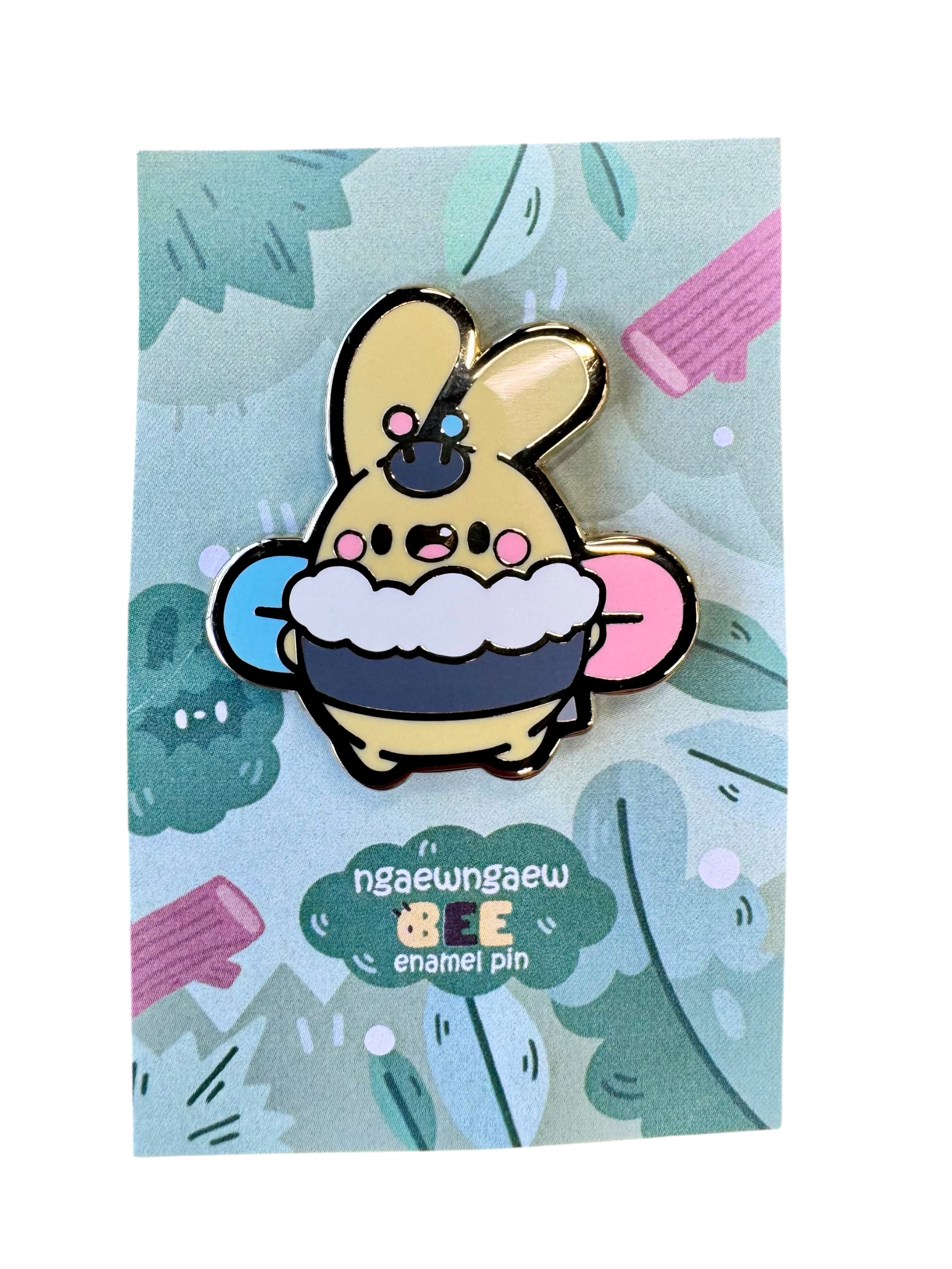 Ngaew Ngaew Bee Pin featuring a cute yellow creature with rounded ears, holding a mug, accented by a bee motif, on a decorative backing card.