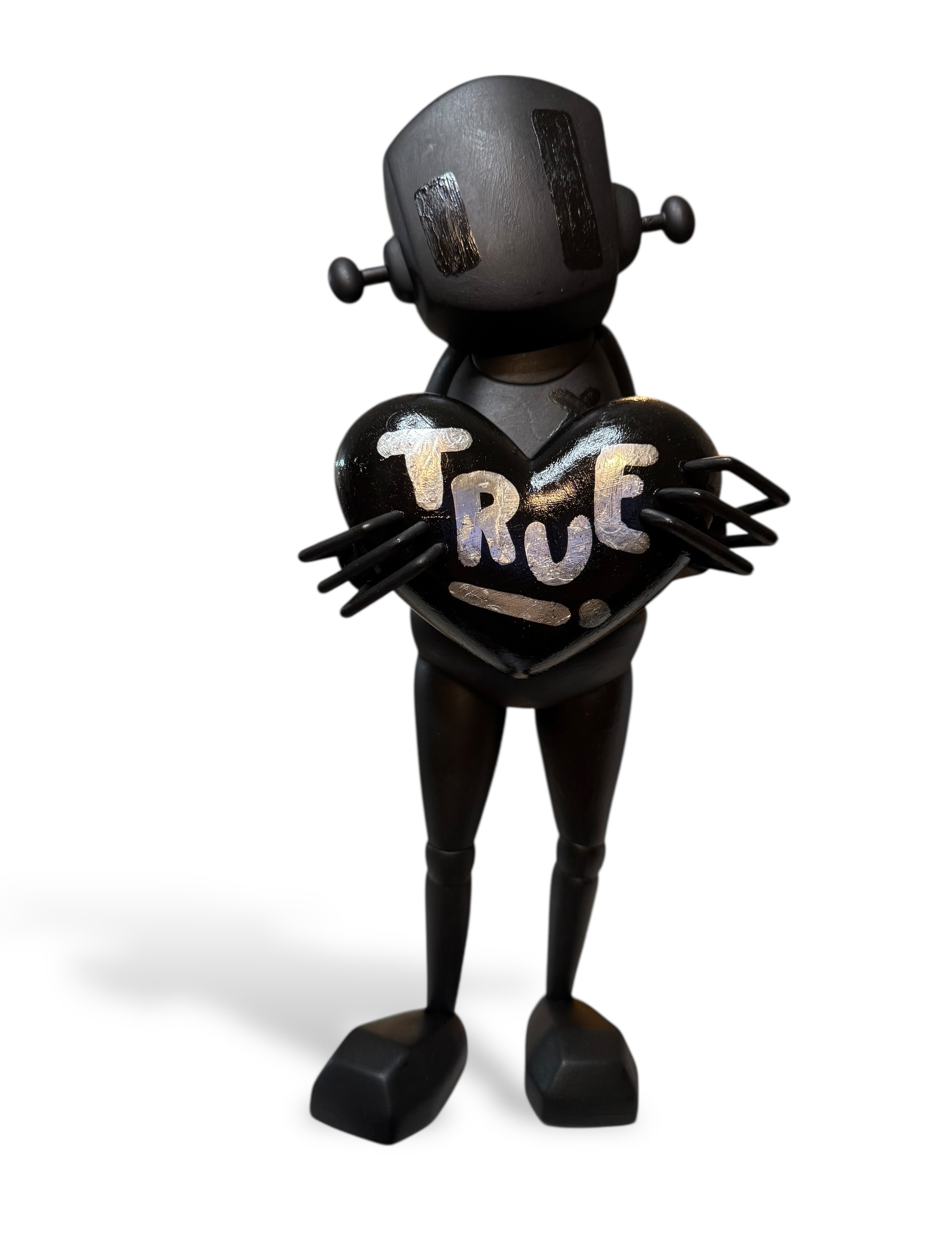 Time Will Tell - Midnight Special by Chris RWK: Matte-black cartoon robot holds a glossy heart with TRUE! in metallic script, features blocky feet and antenna knobs.