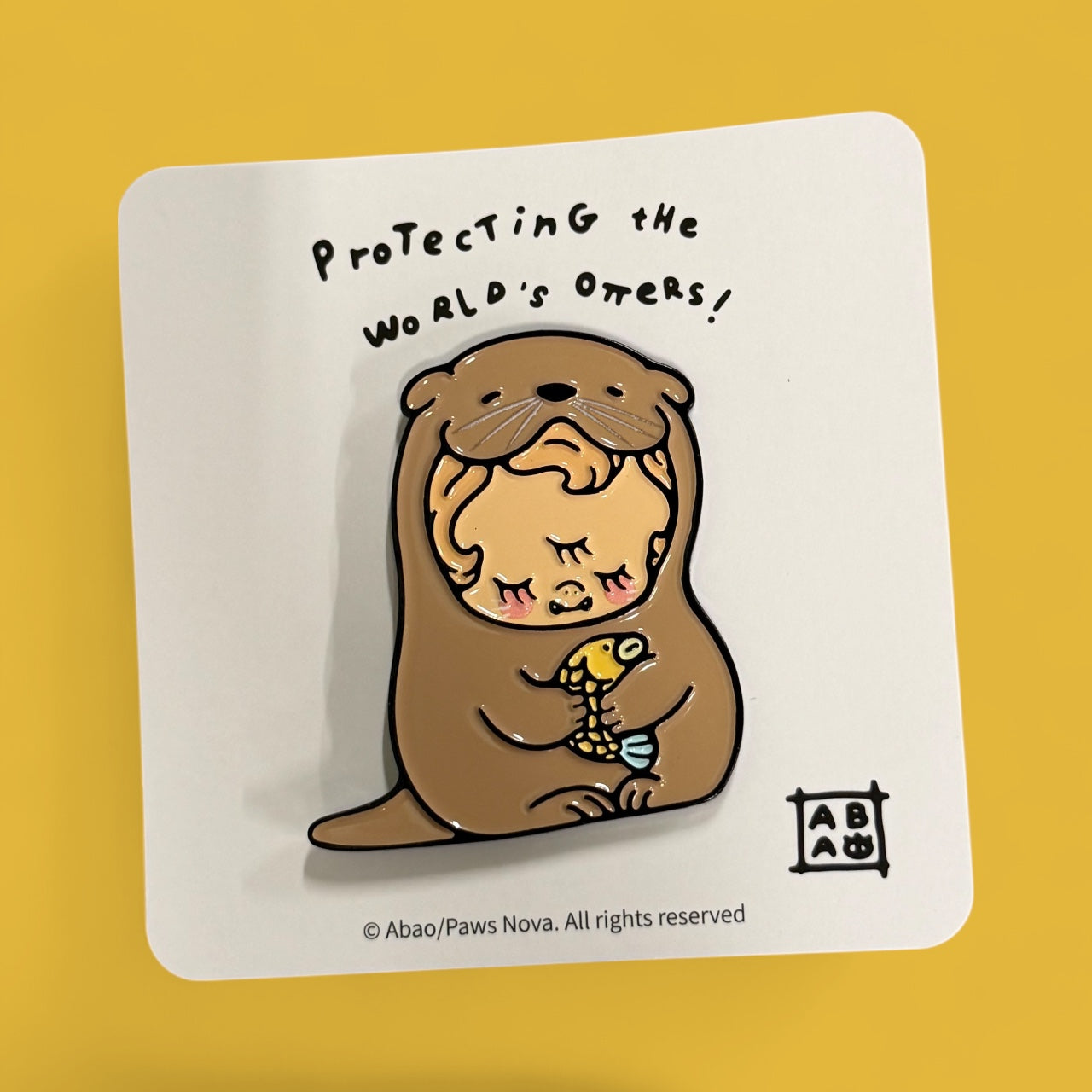 Water Otter DEDE Metal Badge features a figure in an otter suit cradling a fish, with backing card text “Protecting the world’s otters!”