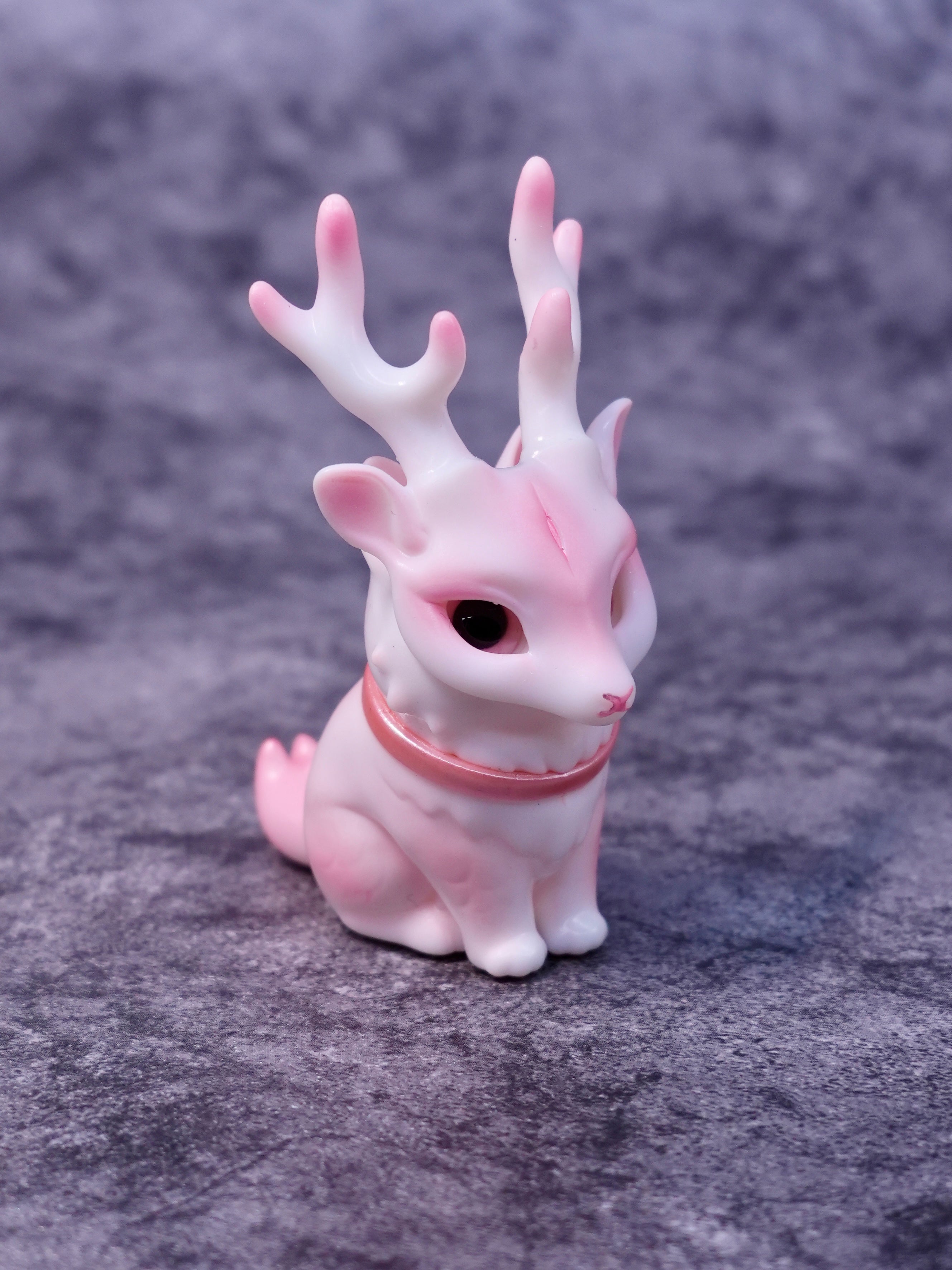 Pink Deer Cat by HOTRU, a fantasy creature figurine with rabbit ears and deer antlers, features a rotating head, sits on velvet, available for preorder.