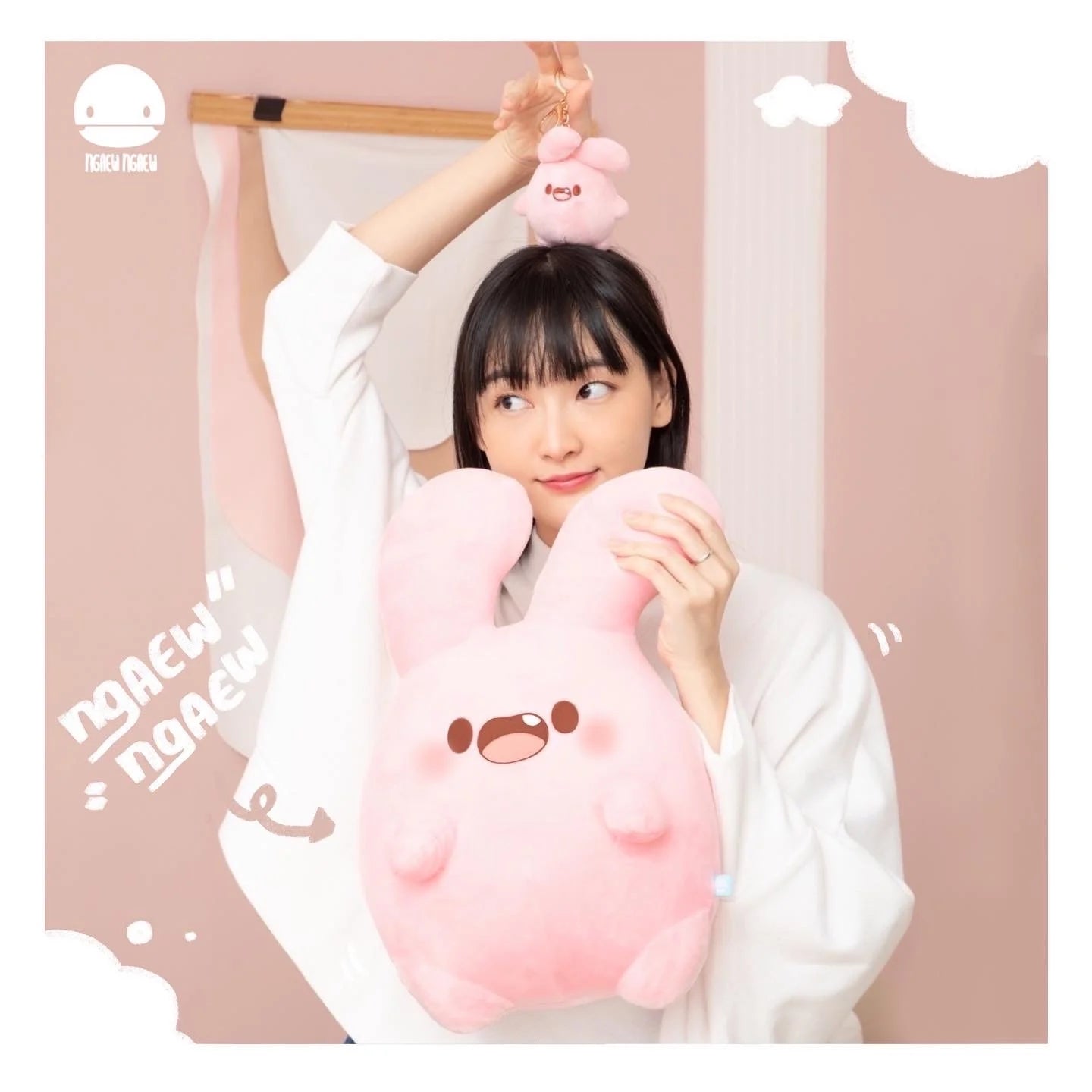 Young woman holds a large Ngaew Ngaew Plush and dangles a smaller matching key-chain version, highlighting the whimsical charm of these pastel bunny toys.