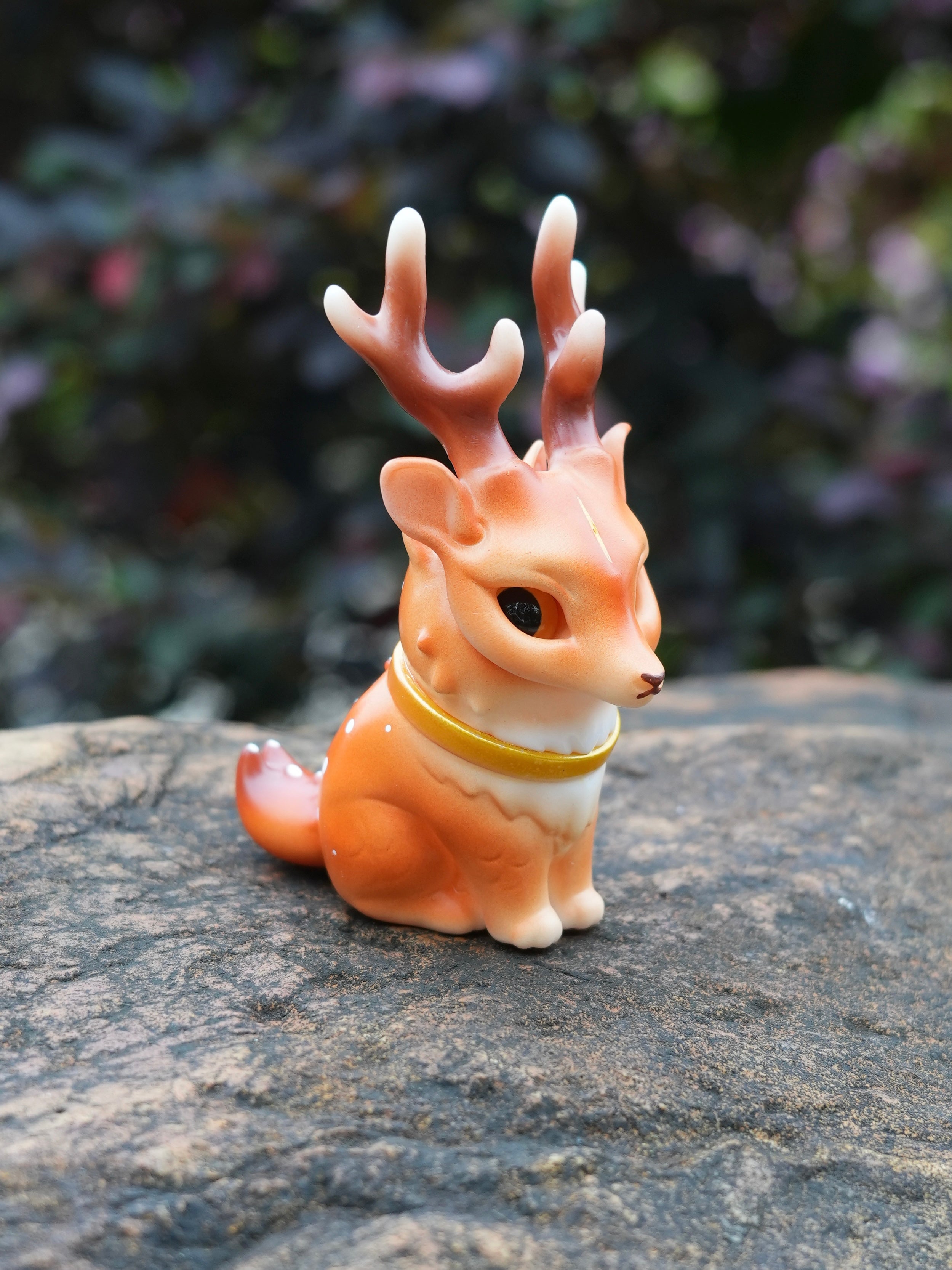 Spotted Deer Cat by HOTRU - Preorder: A fox-like figurine with deer antlers, painted in warm tones, wearing a collar, sitting on a rock.