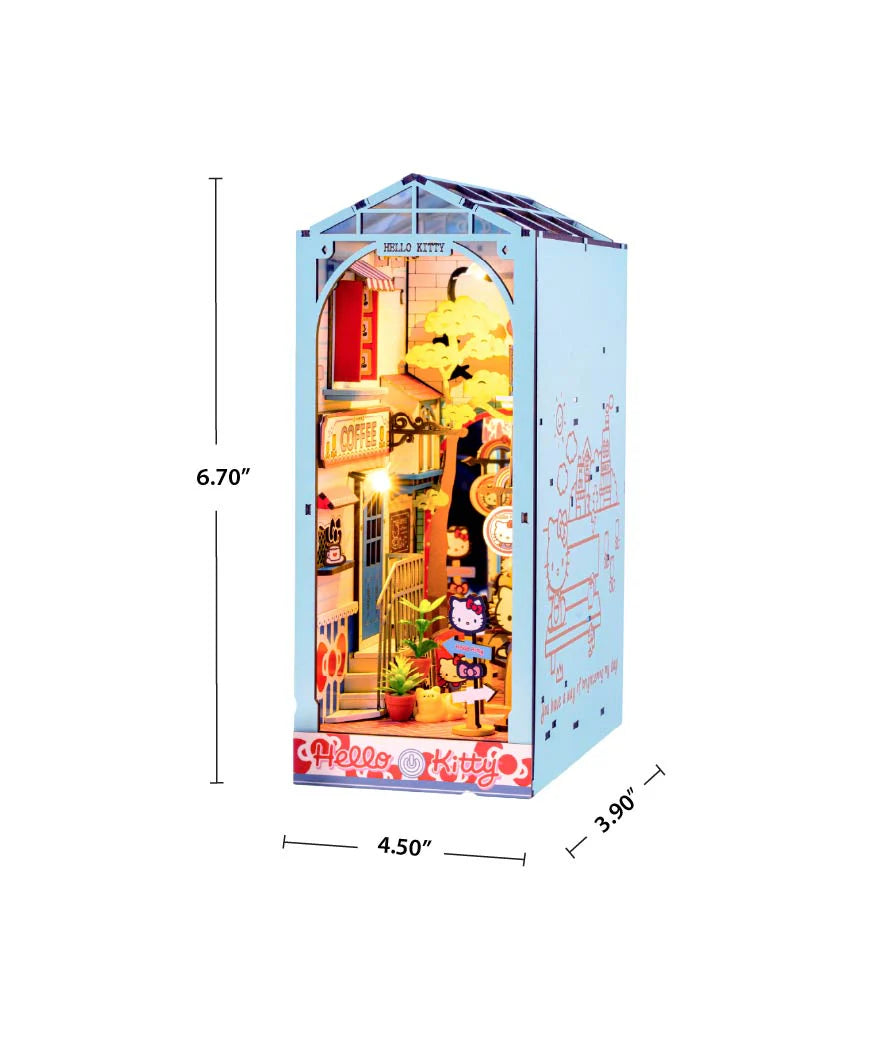 Hello Kitty® Town Square Booknook, a 3-D DIY kit featuring a café scene with Hello Kitty figurines, LED lights, and intricate details in a house-shaped enclosure.