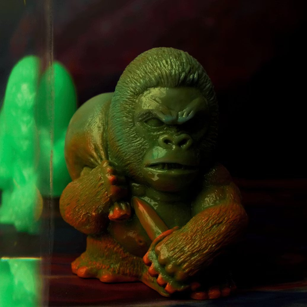 Retroband & Zectron's WHO GOES THERE? VERSUS features a glossy green gorilla figurine, posed dynamically with a club, highlighted by dramatic lighting.