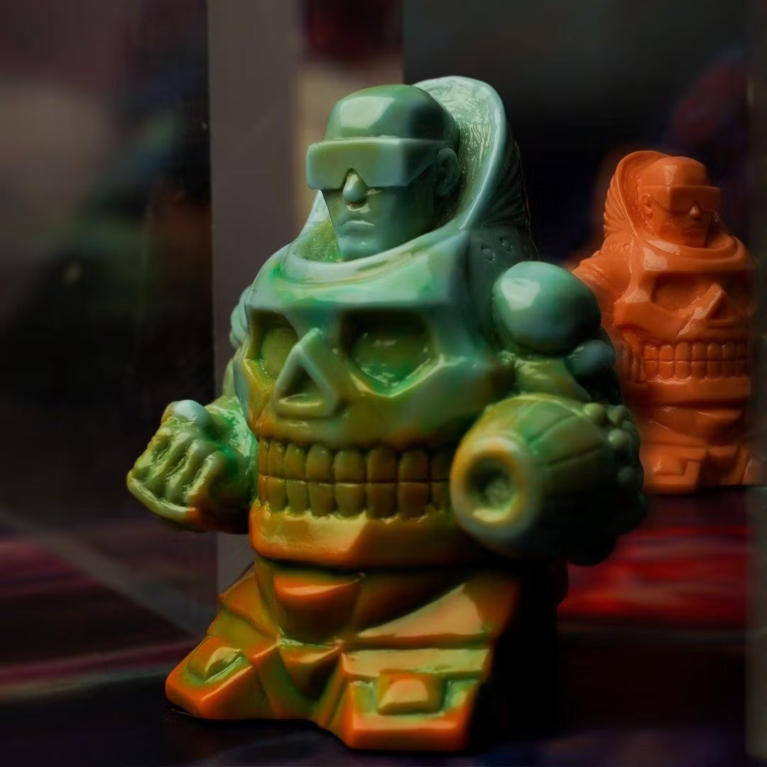 Retroband & Zectron's WHO GOES THERE? VERSUS features two small resin figures, a futuristic soldier/skull hybrid, with one in green-orange gradient and another in solid orange.