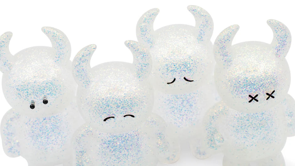 UAMOU WHITE OPAL: Four small, horned vinyl figures with unique painted faces, crafted from translucent, glitter-filled plastic, each measuring 7cm.